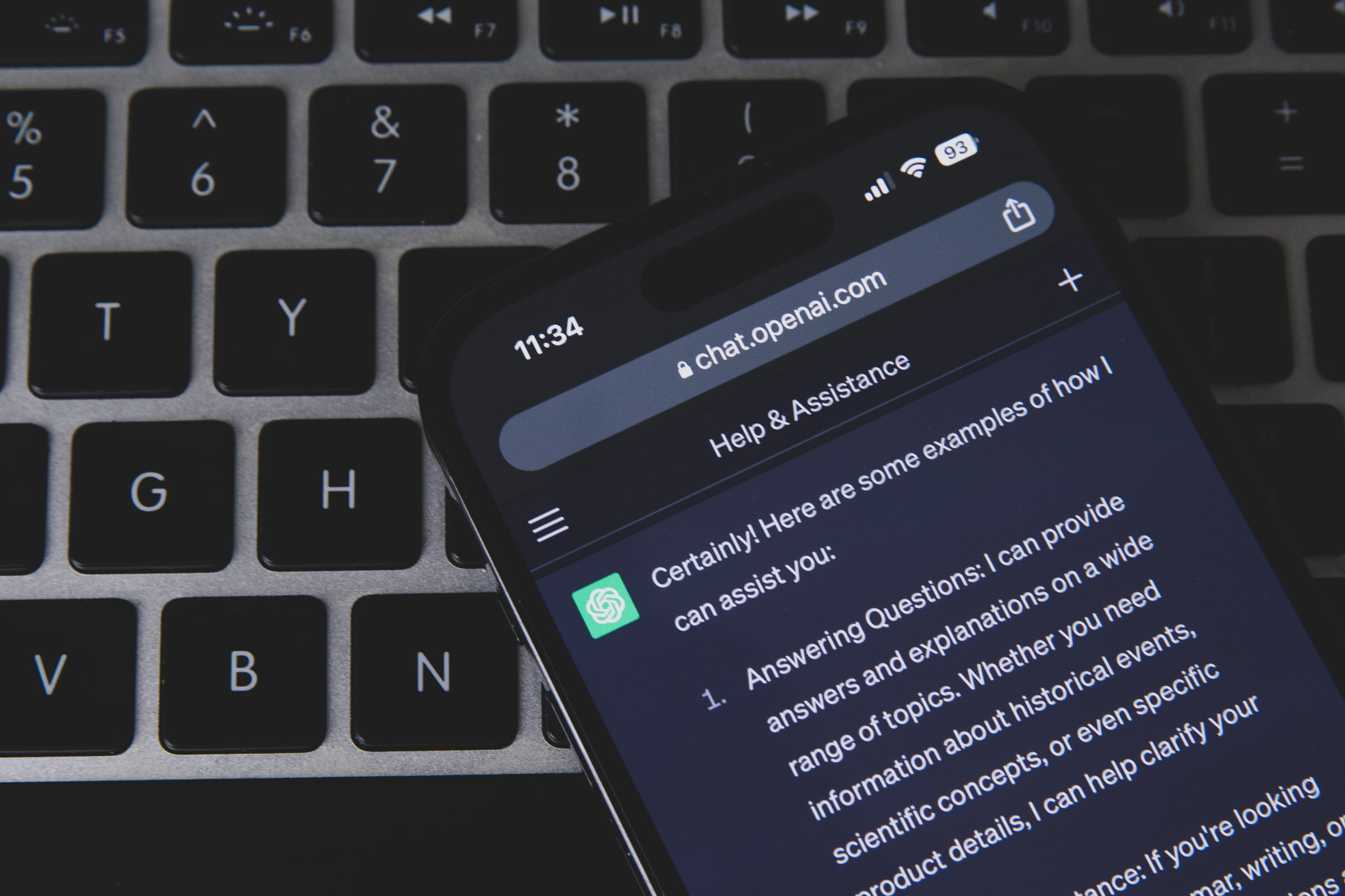 A smartphone displaying ChatGPT rests on a computer keyboard.