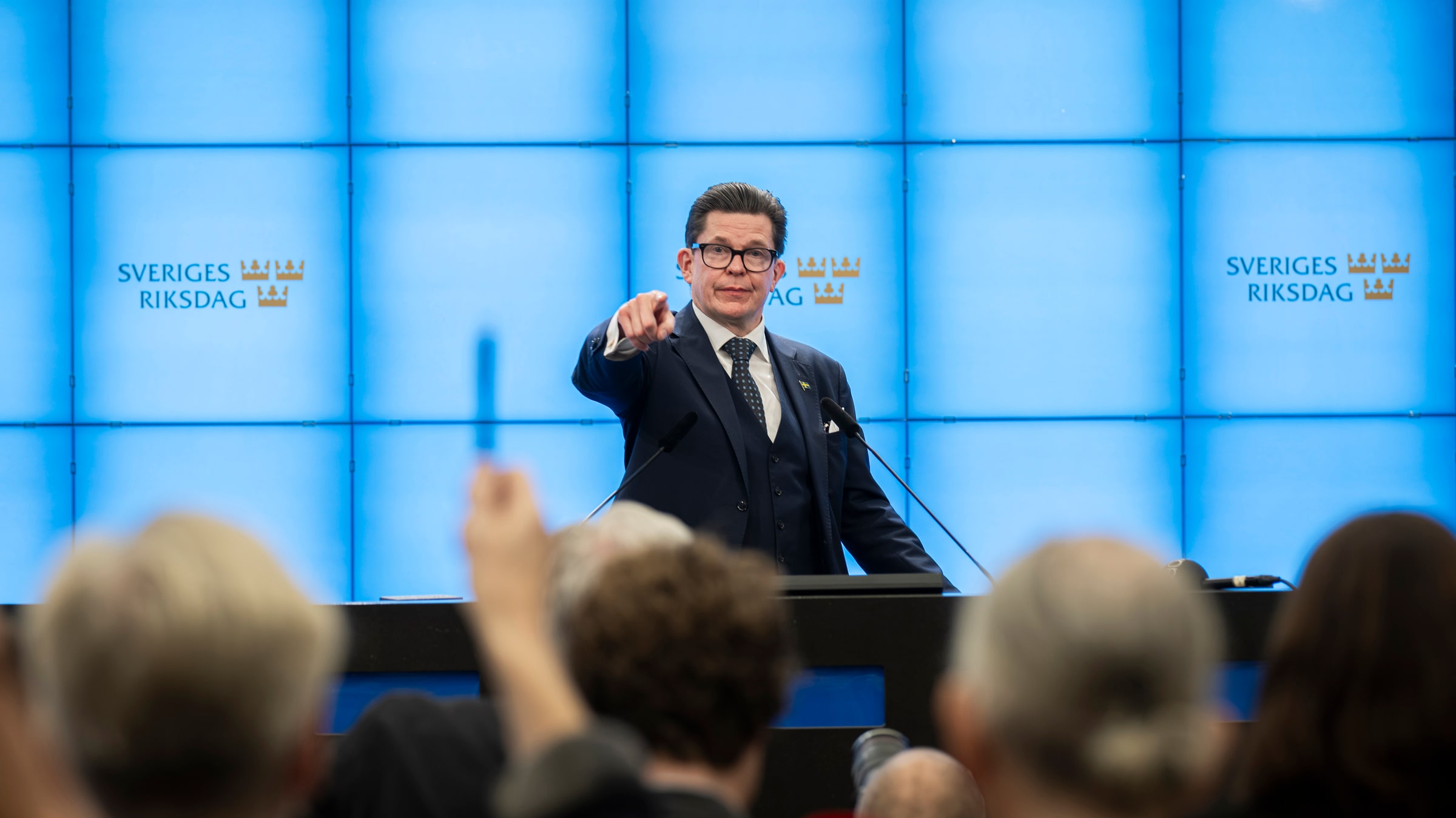 Andreas Norlén pointing towards journalists at a Riksdag press conference on 13 October 2026.