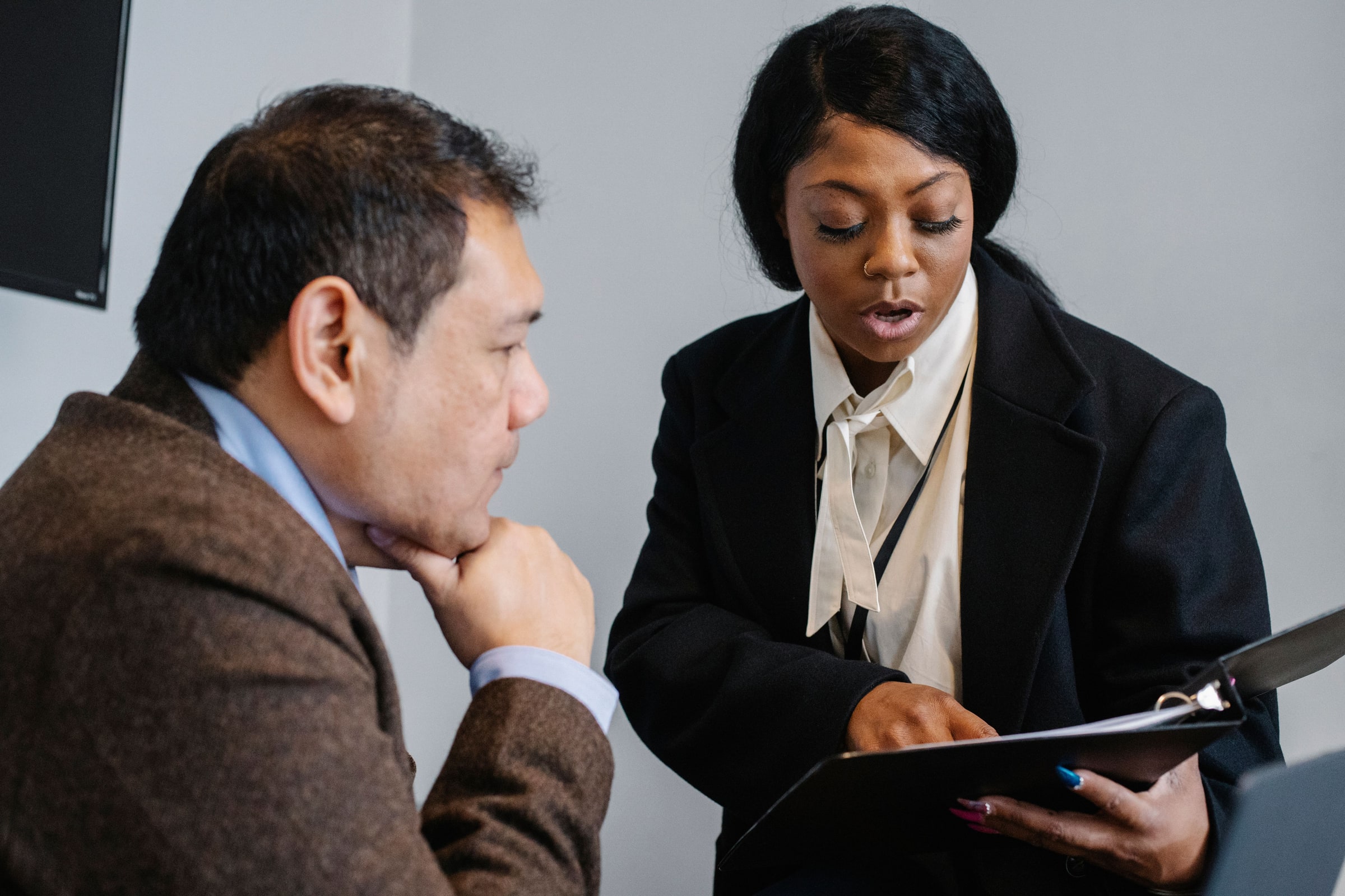 Two people examine a folder together.