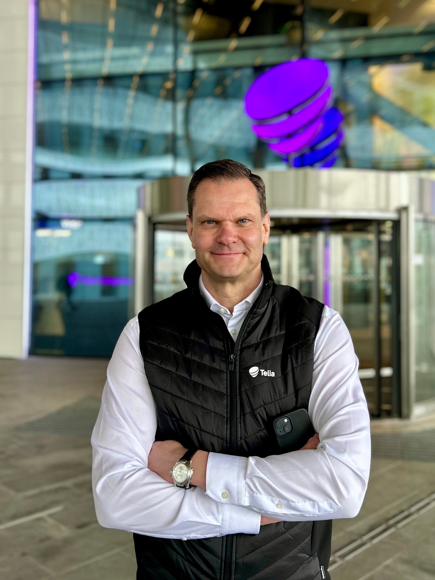 Patrik Hofbauer standing with folded arms outside a Telia entrance in Solna.