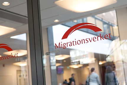 The red Migrationsverket name and bridge symbol displayed on a glass office wall.
