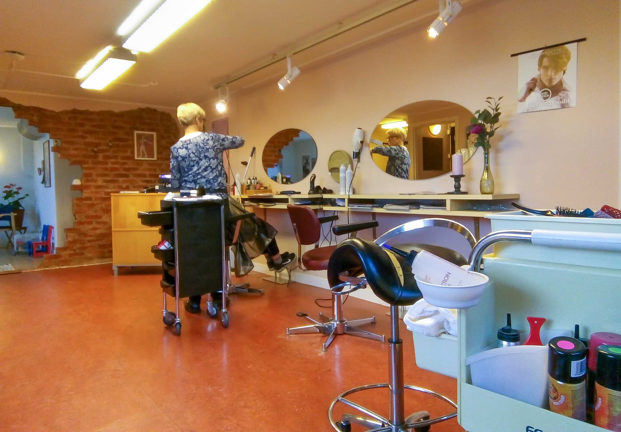 A hairdresser works with a customer inside a salon in Brastad, Sweden, in October 2018.