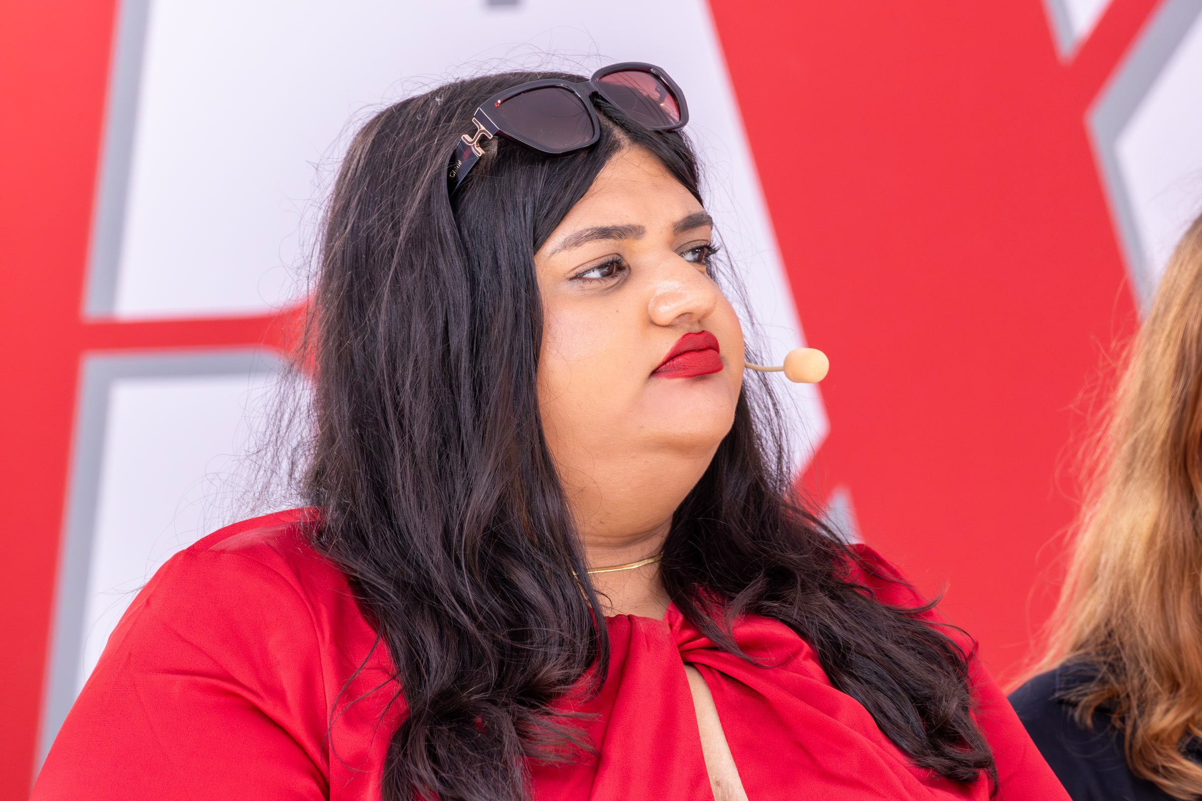 Moska Hassas wearing a headset microphone and listening at an outdoor panel.