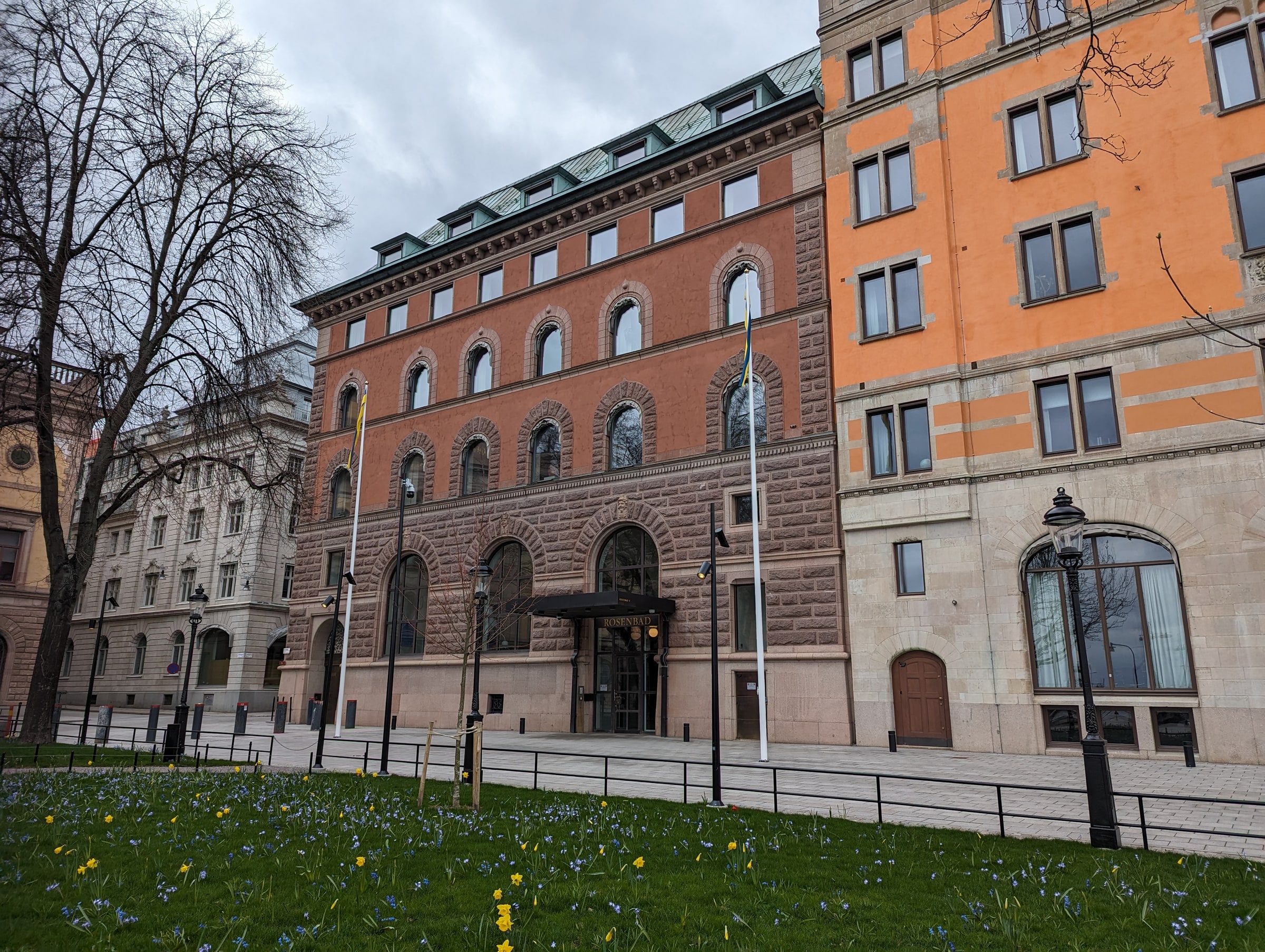 Rosenbad’s orange and stone facade, arched windows and entrance beside a paved walkway.