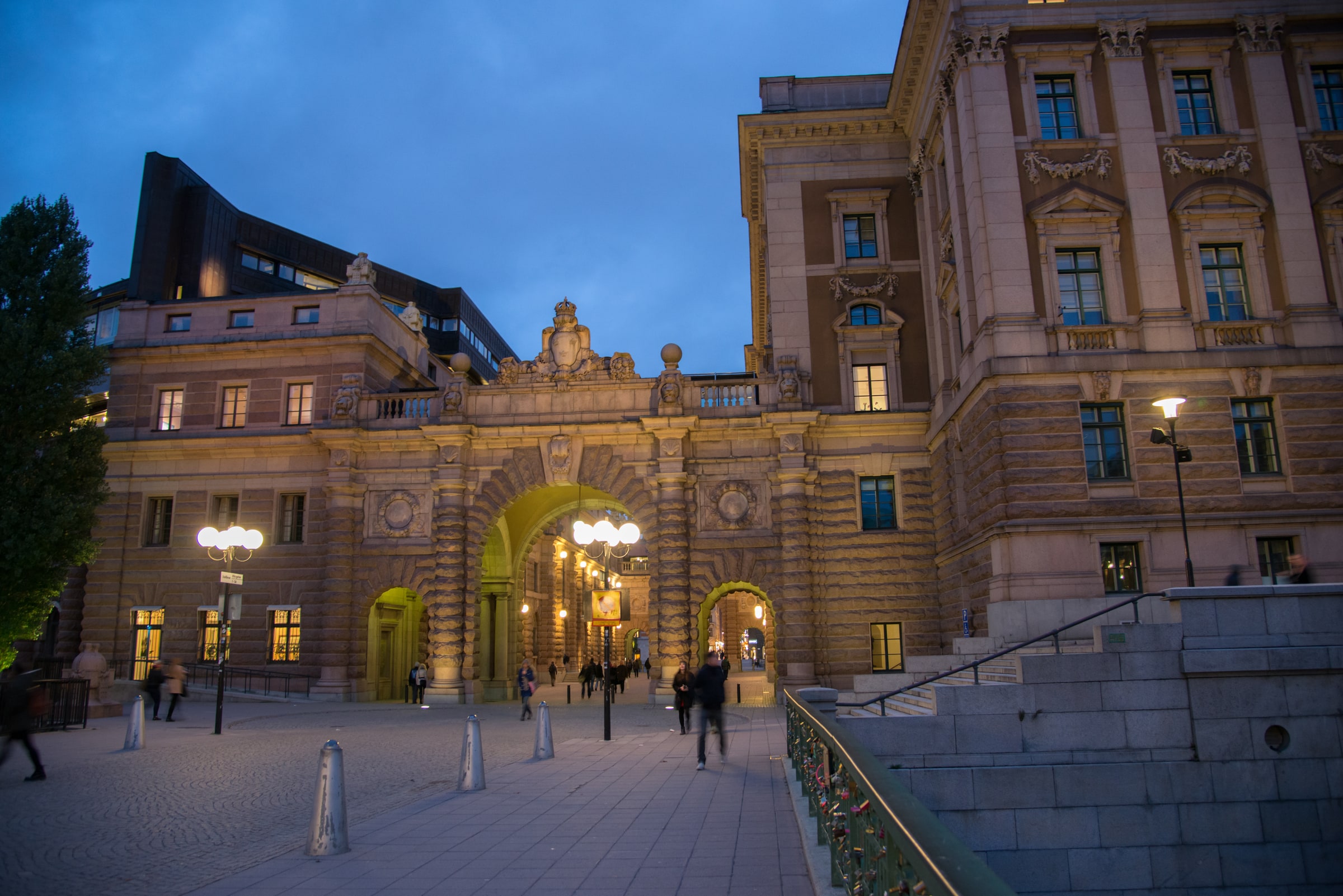 The Riksdag complex and illuminated public archway in central Stockholm at dusk.