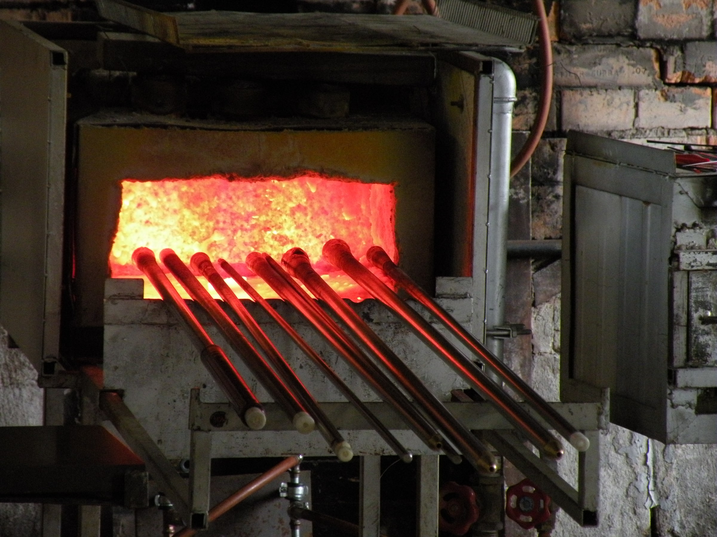 A glowing furnace and glassblowing pipes at Bergdala glassworks in Sweden.