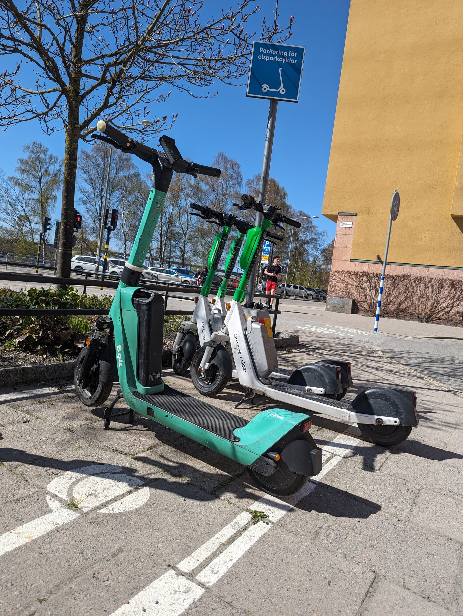 Electric scooters parked beside a yellow building on Pilgatan in Stockholm.