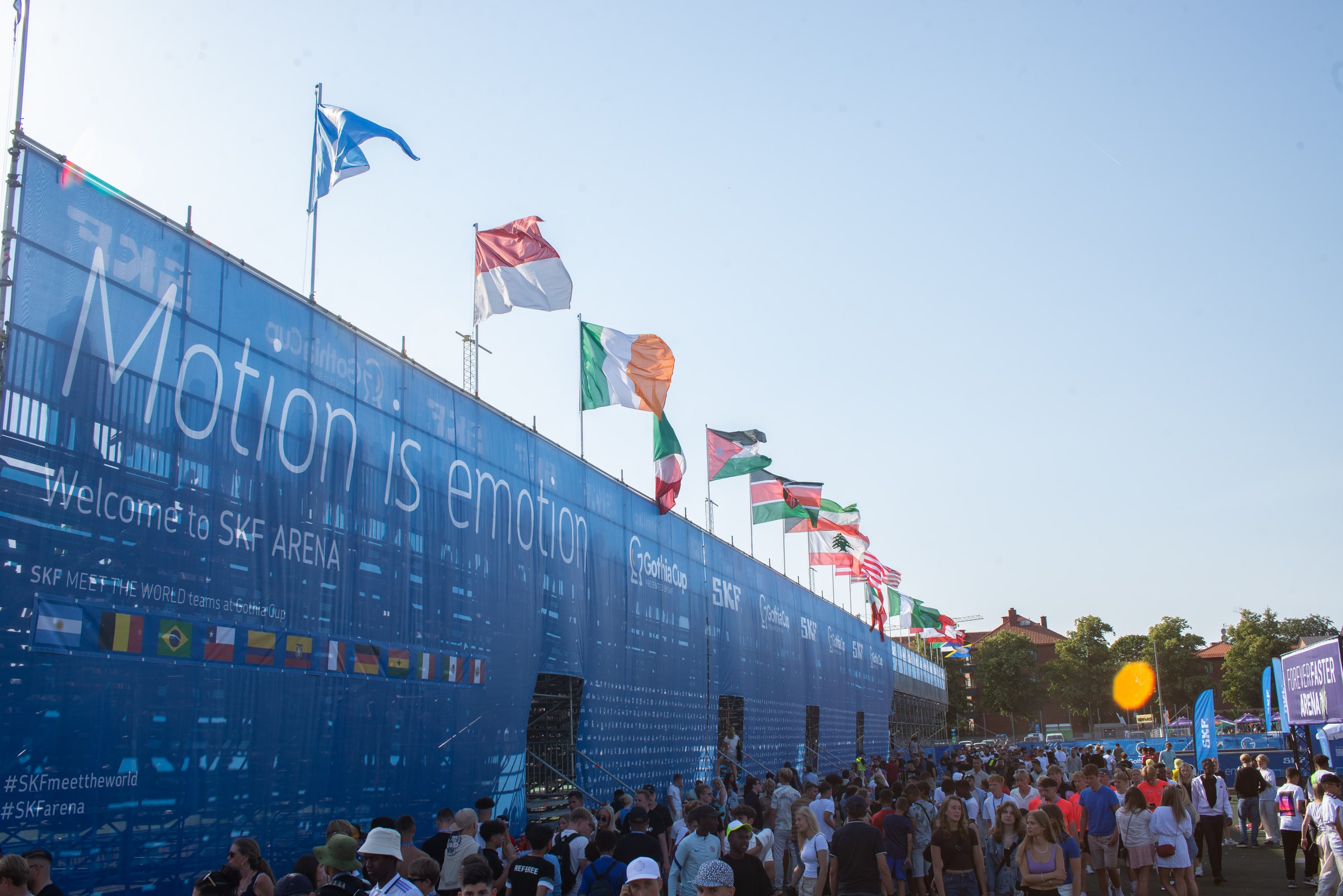 International flags line the SKF Arena at Heden as Gothia Cup visitors walk below.