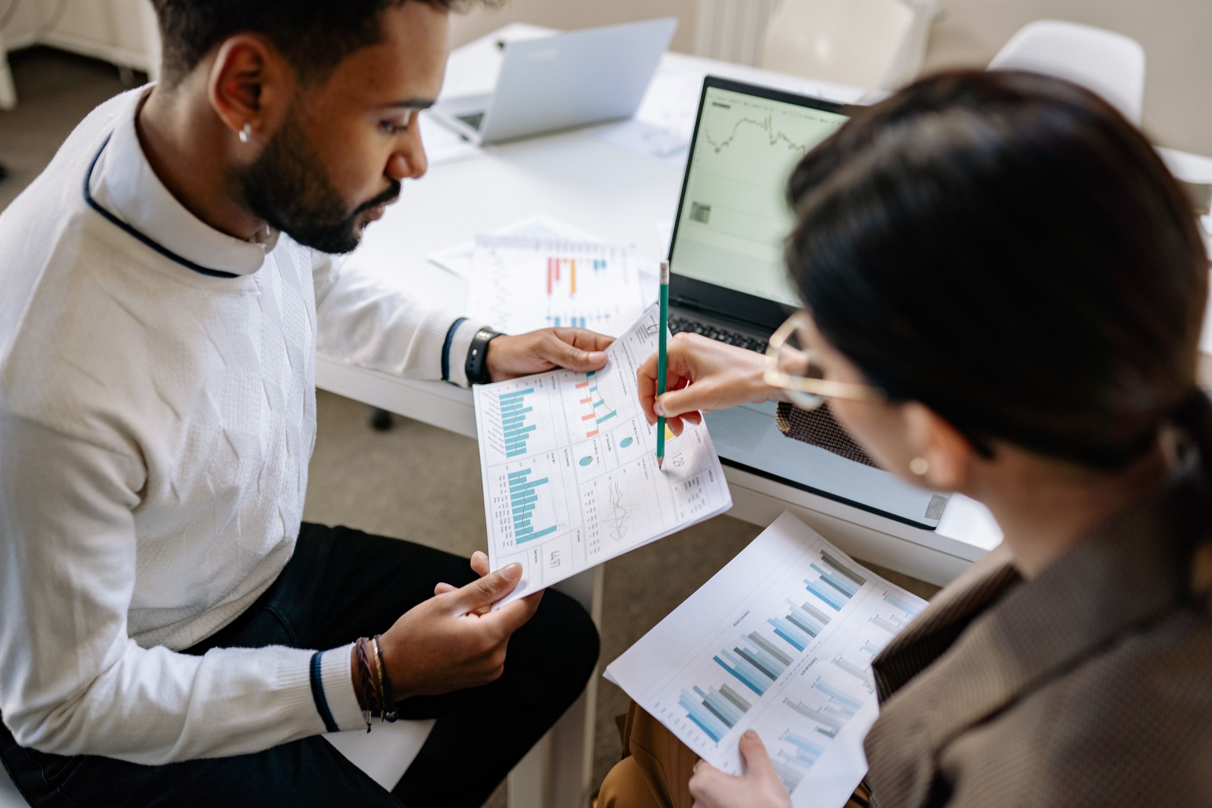 Two professionals review printed charts at a table in an office.