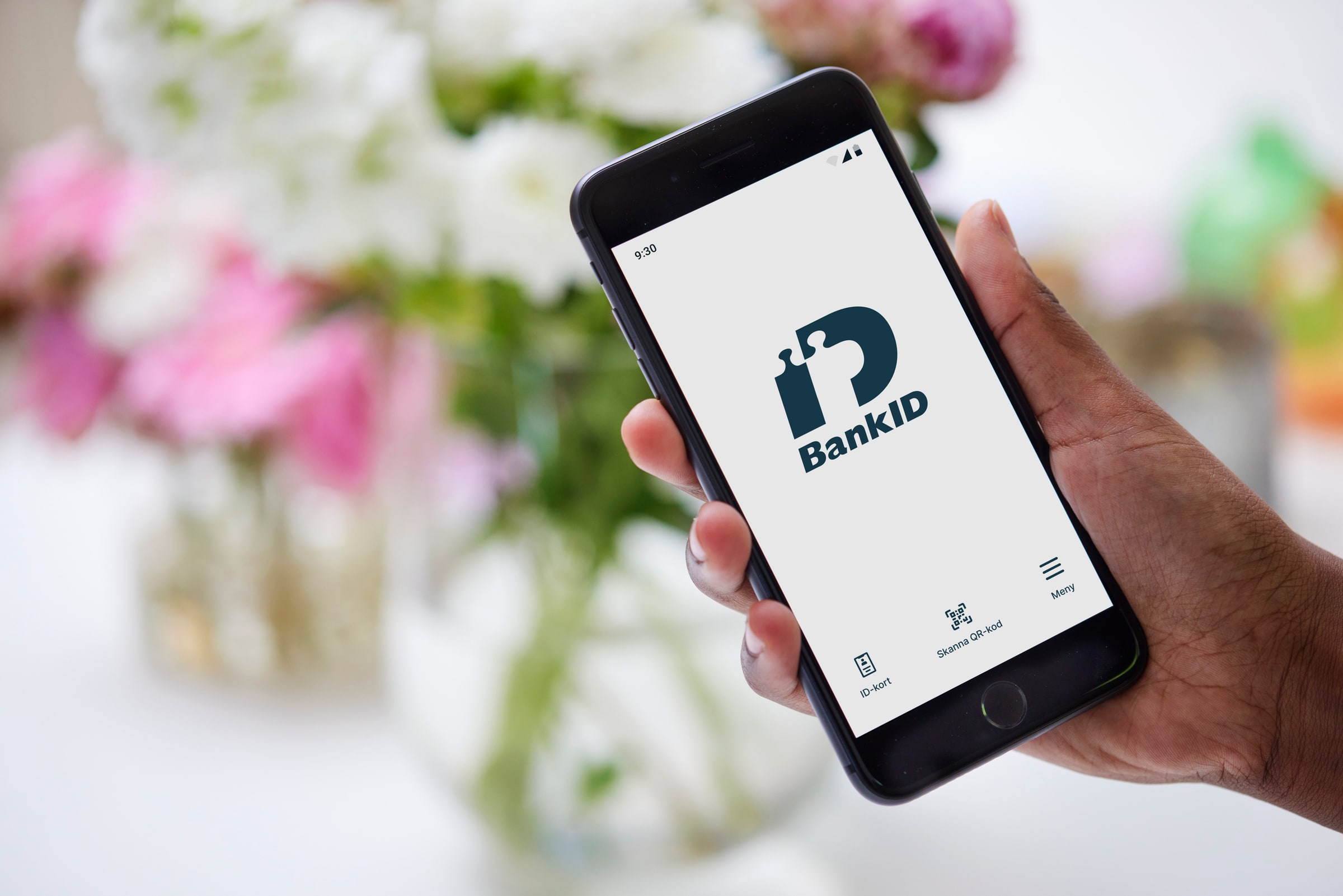 An anonymous hand holds a real phone displaying the Swedish BankID app and Swedish-language controls.