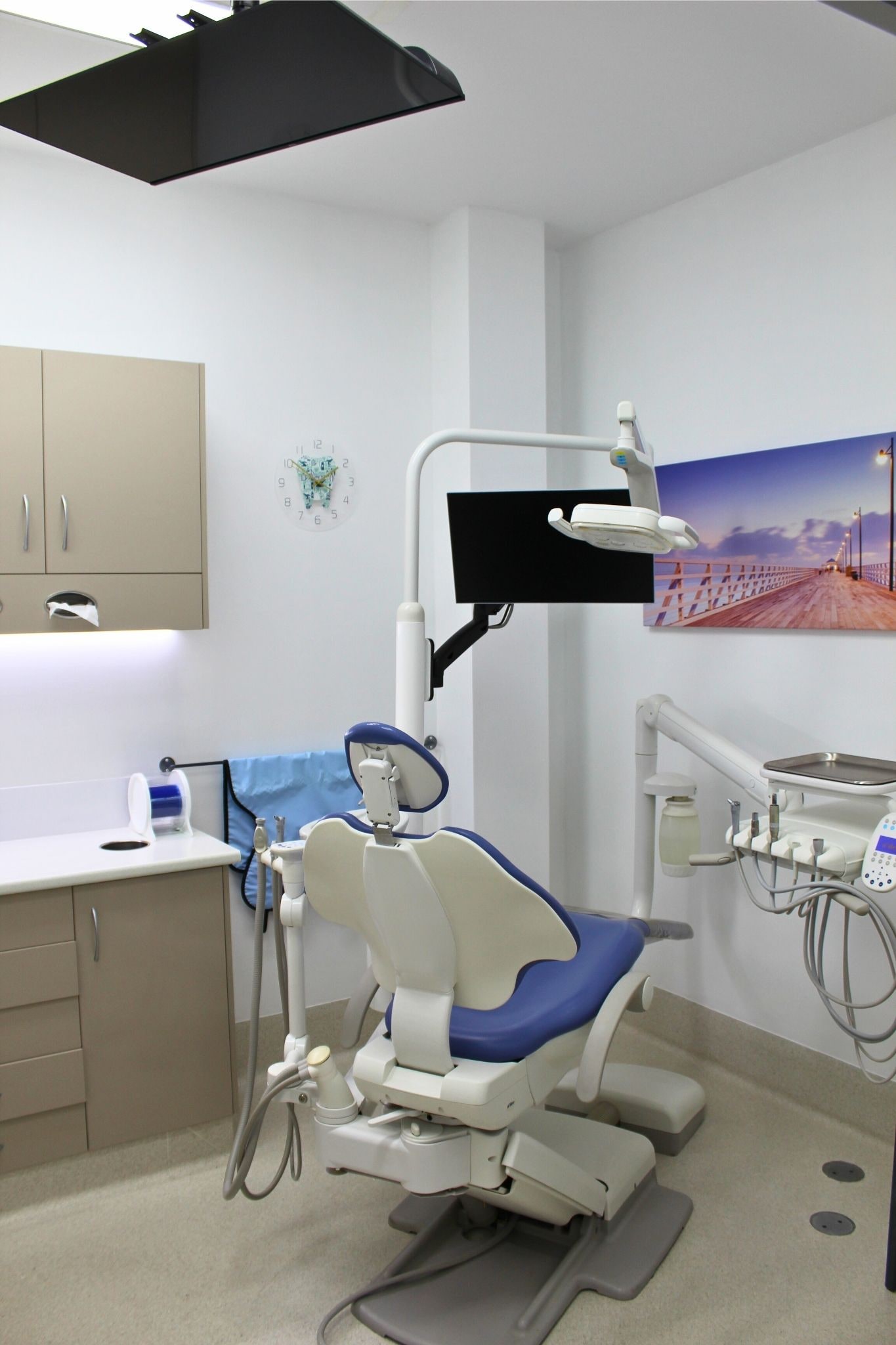 An empty dental treatment room with a chair, examination light and instruments.