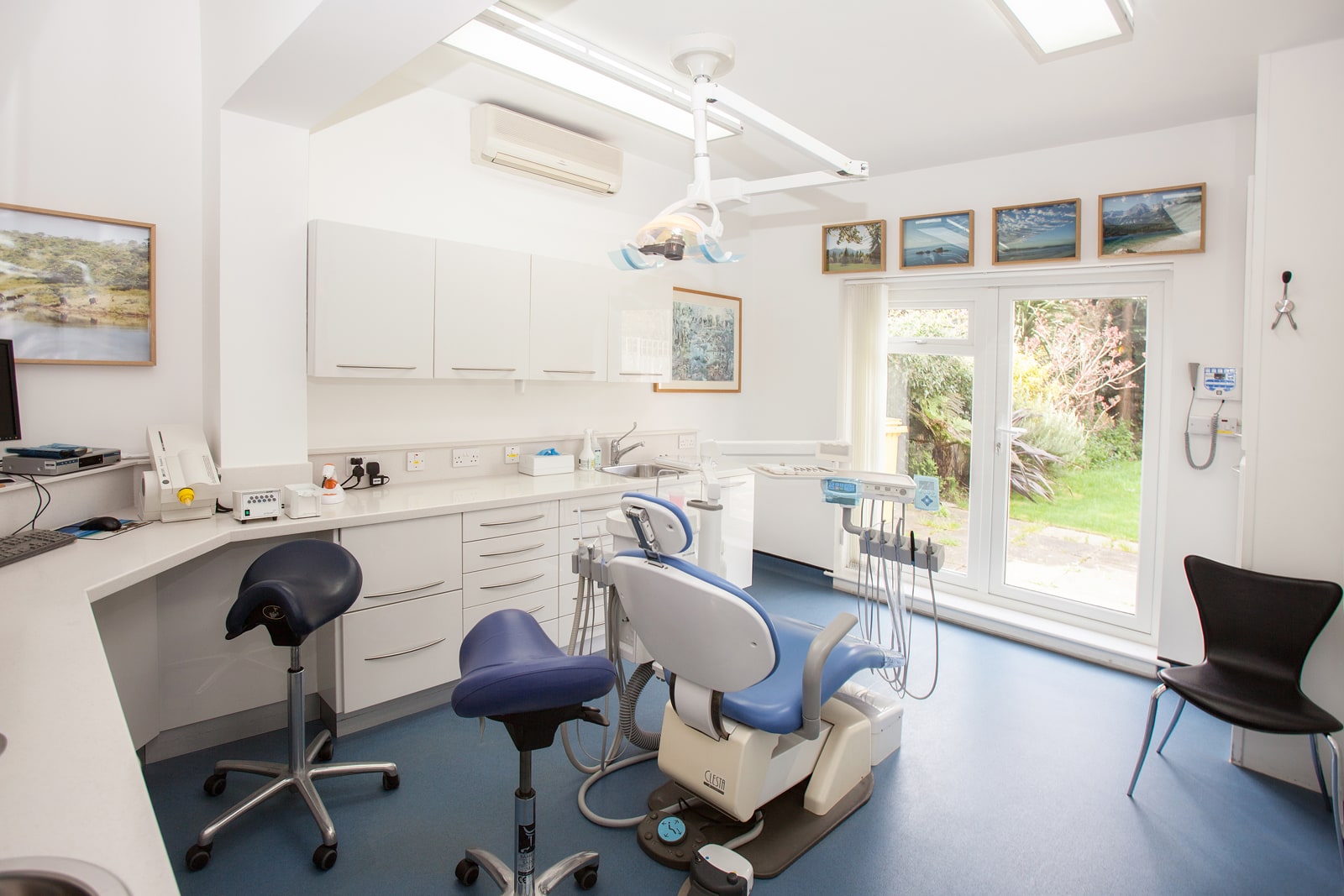 An empty dental treatment room with a chair, overhead light and clinical instruments.