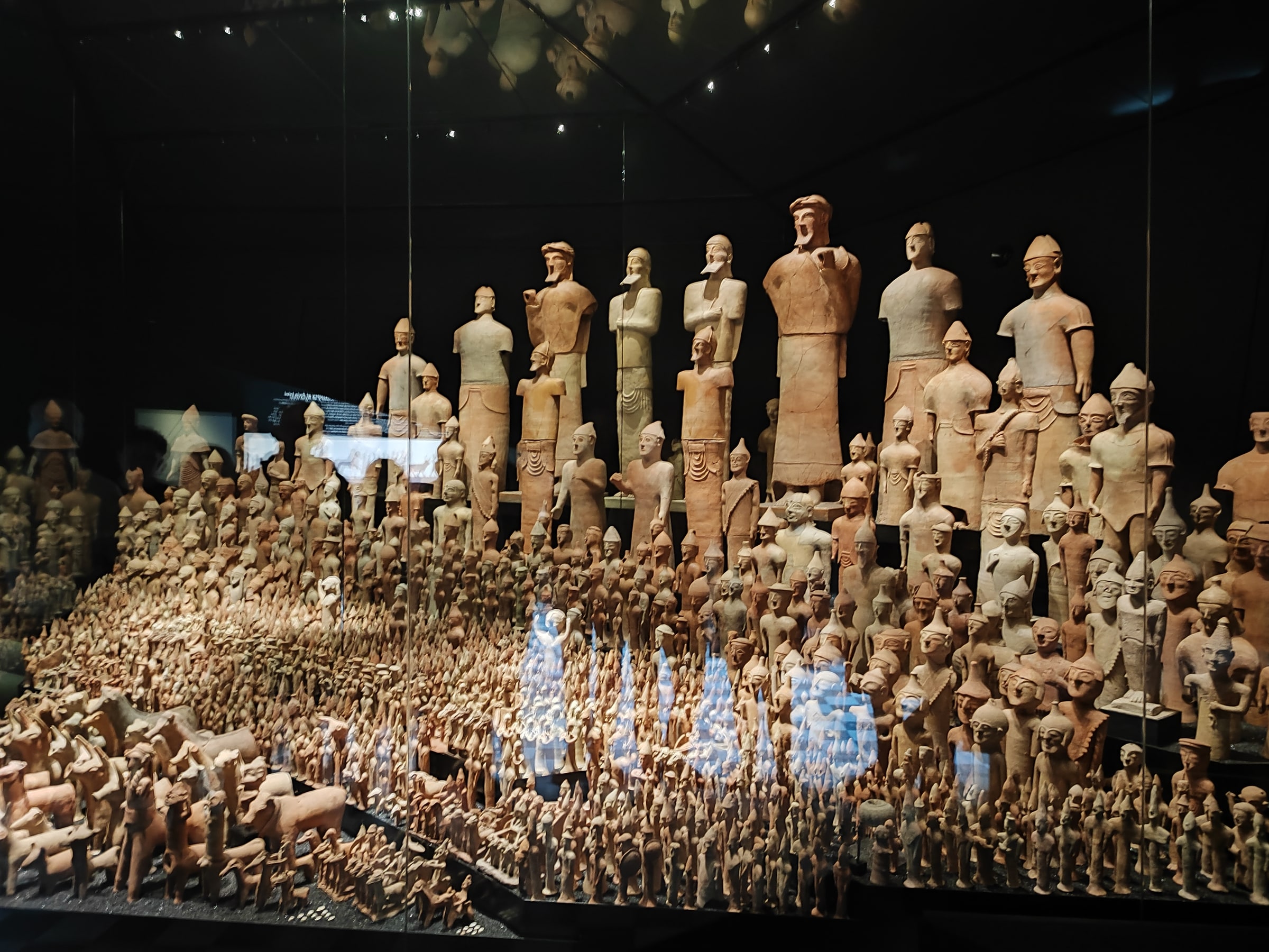Terracotta figures displayed together behind glass at Stockholm’s Mediterranean Museum.