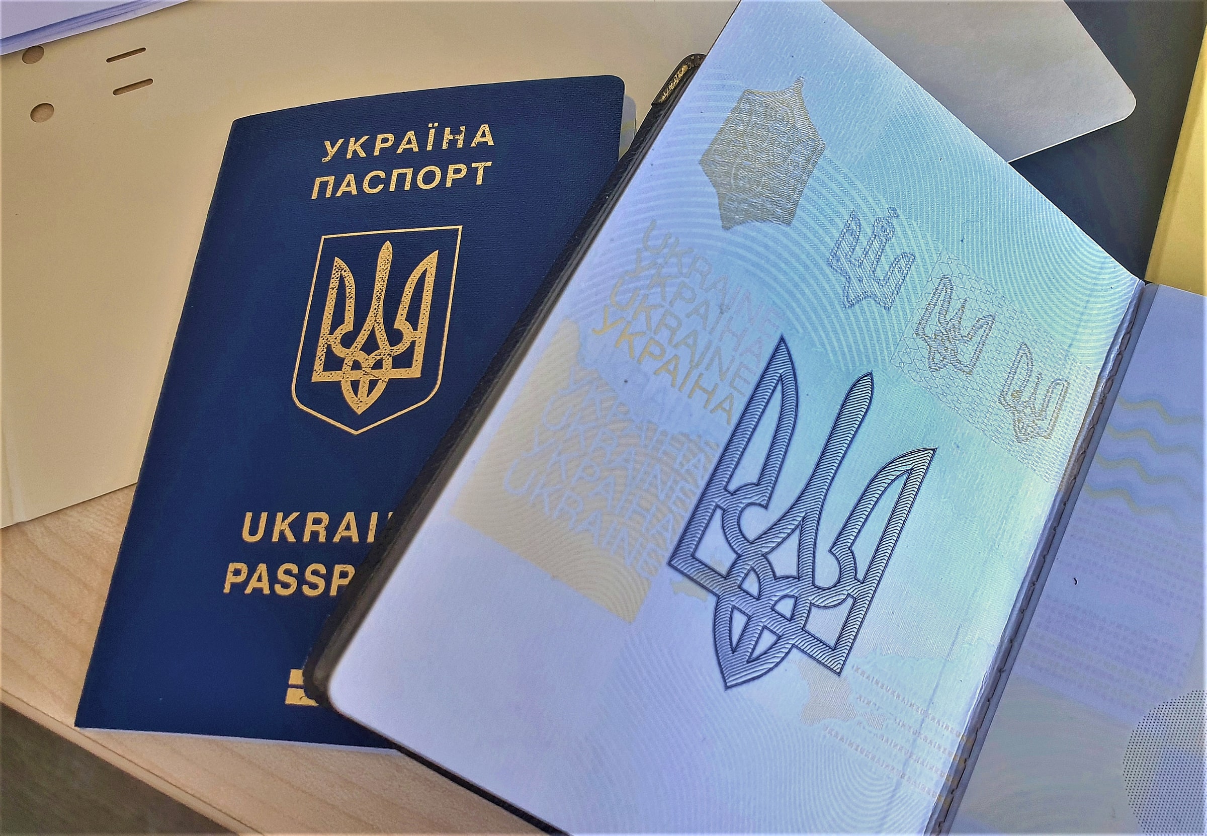 Two Ukrainian passports, one open to a decorative coat-of-arms page.