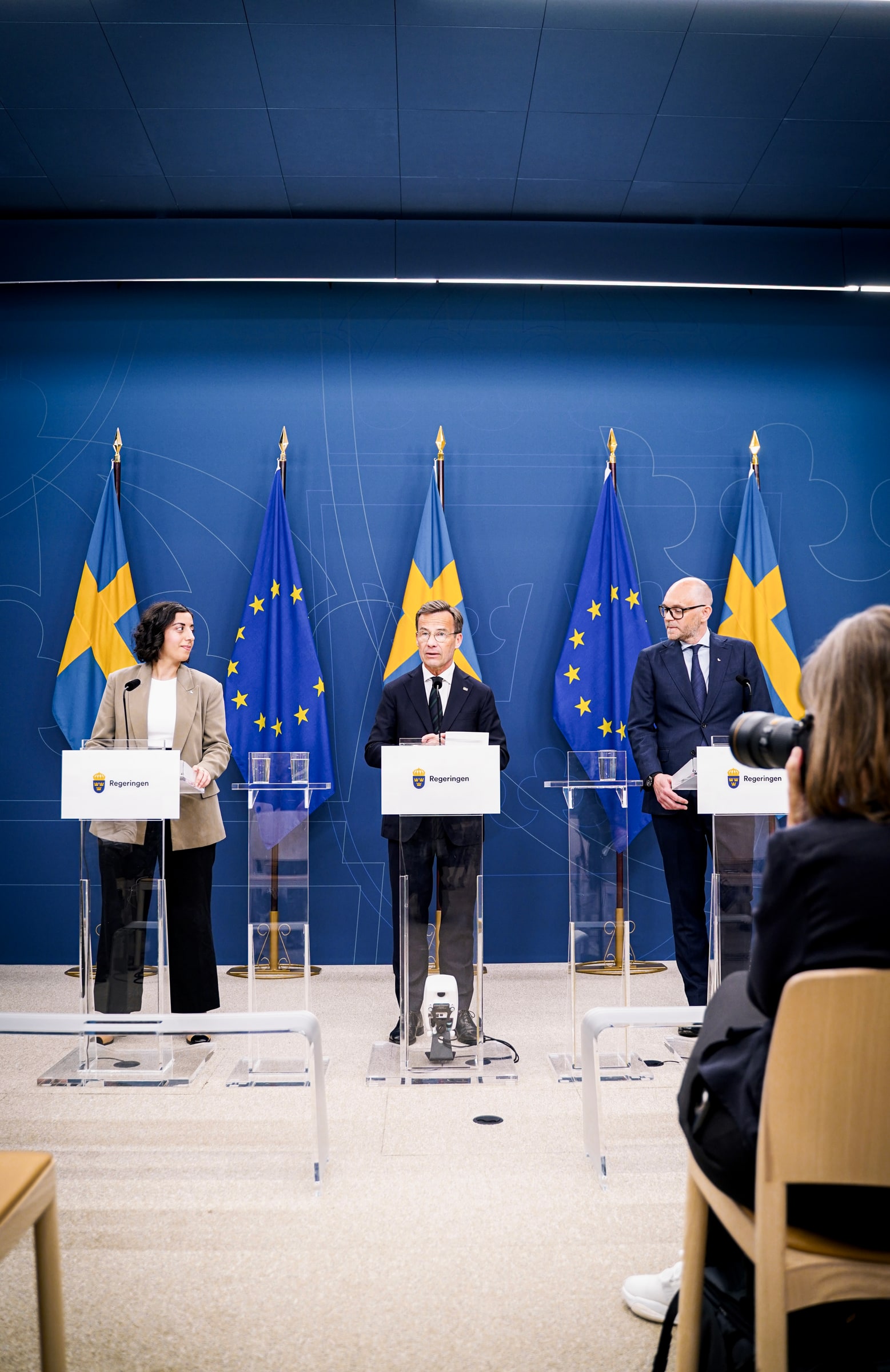 Simona Mohamsson and Ulf Kristersson stand at lecterns during a government press conference.