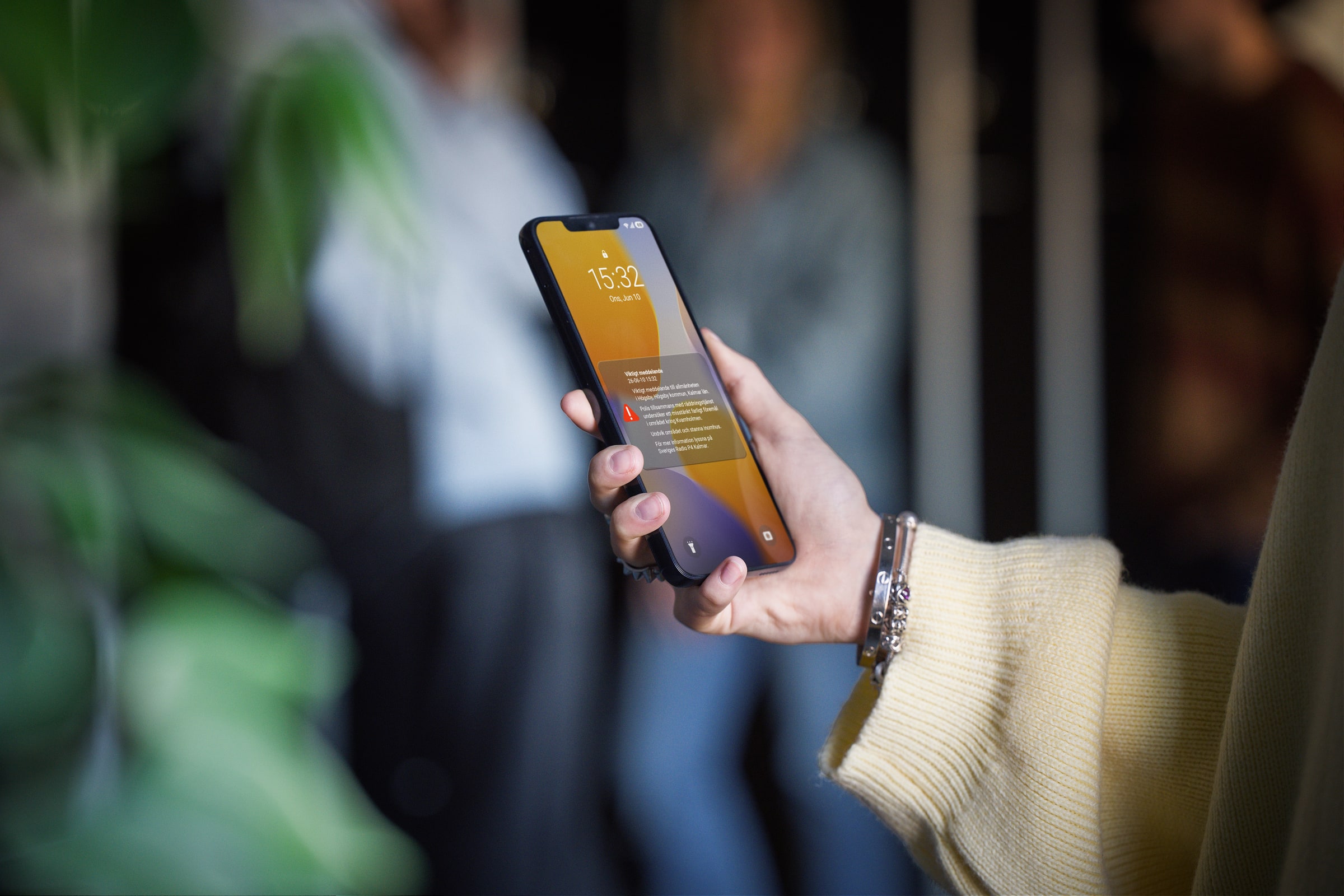 A hand holds a smartphone displaying a Swedish SE-Alert warning message.