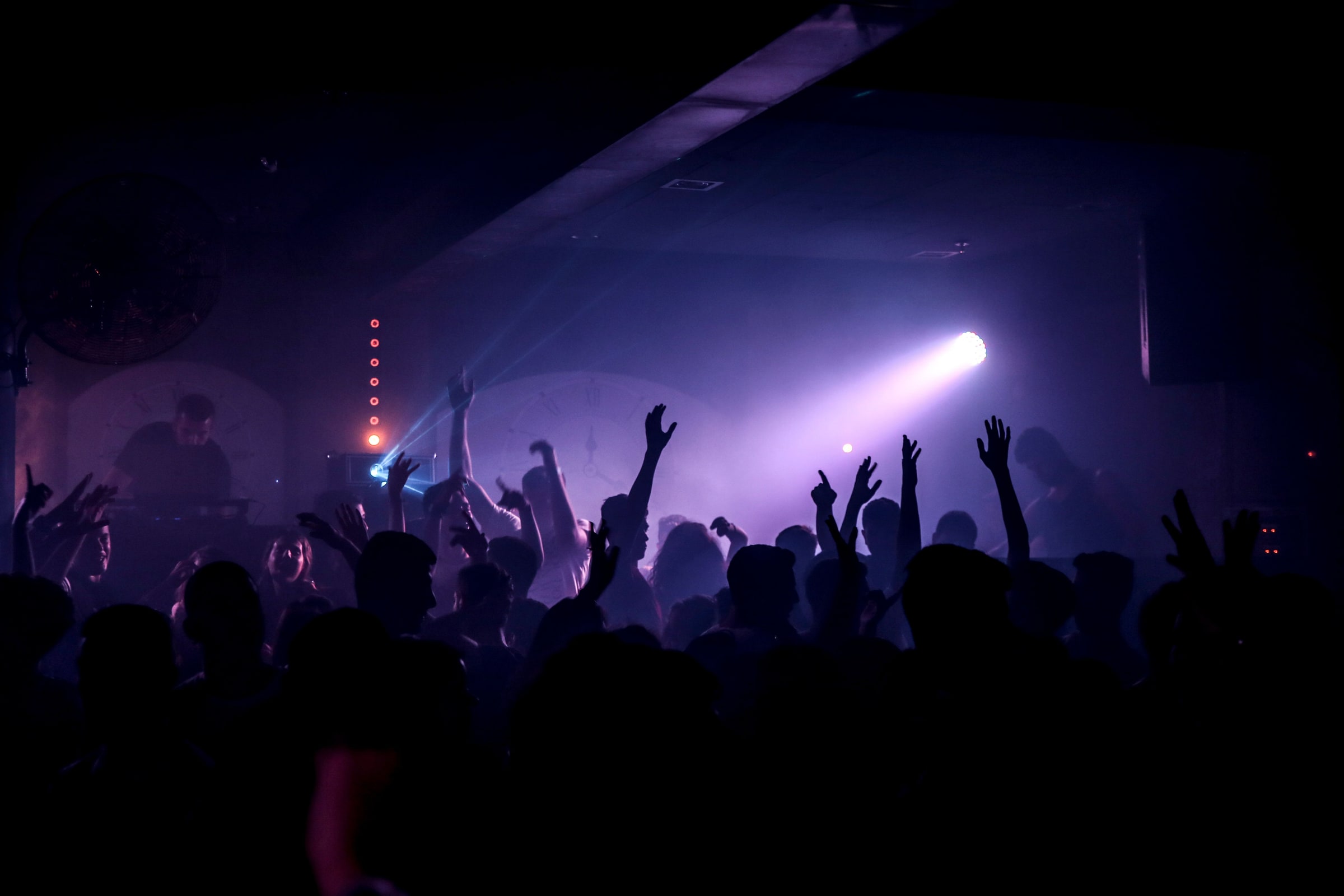 A nightclub crowd dancing beneath purple stage lights.