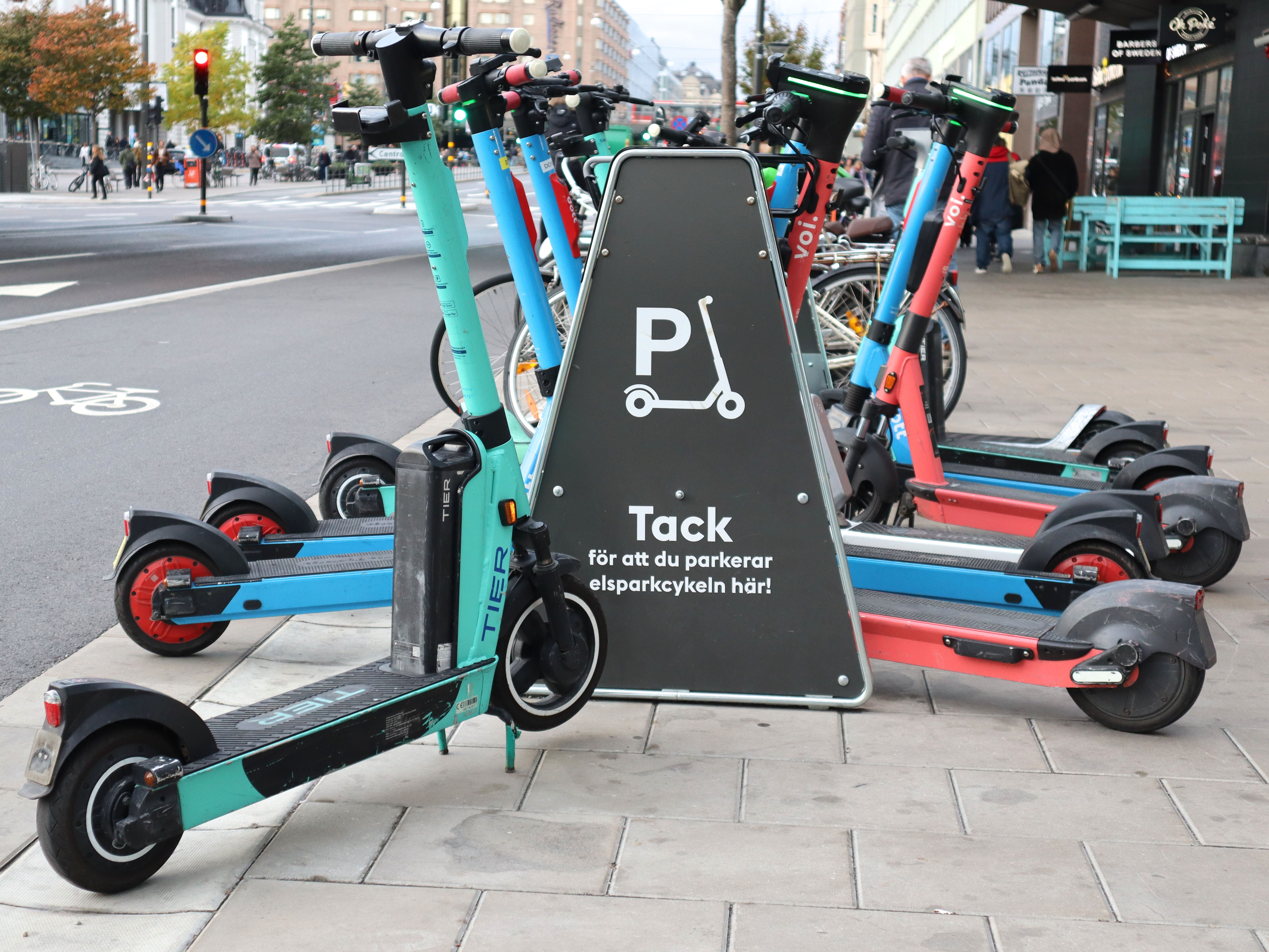 Rental e-scooters stand around a marked parking rack on Vasagatan in Stockholm.
