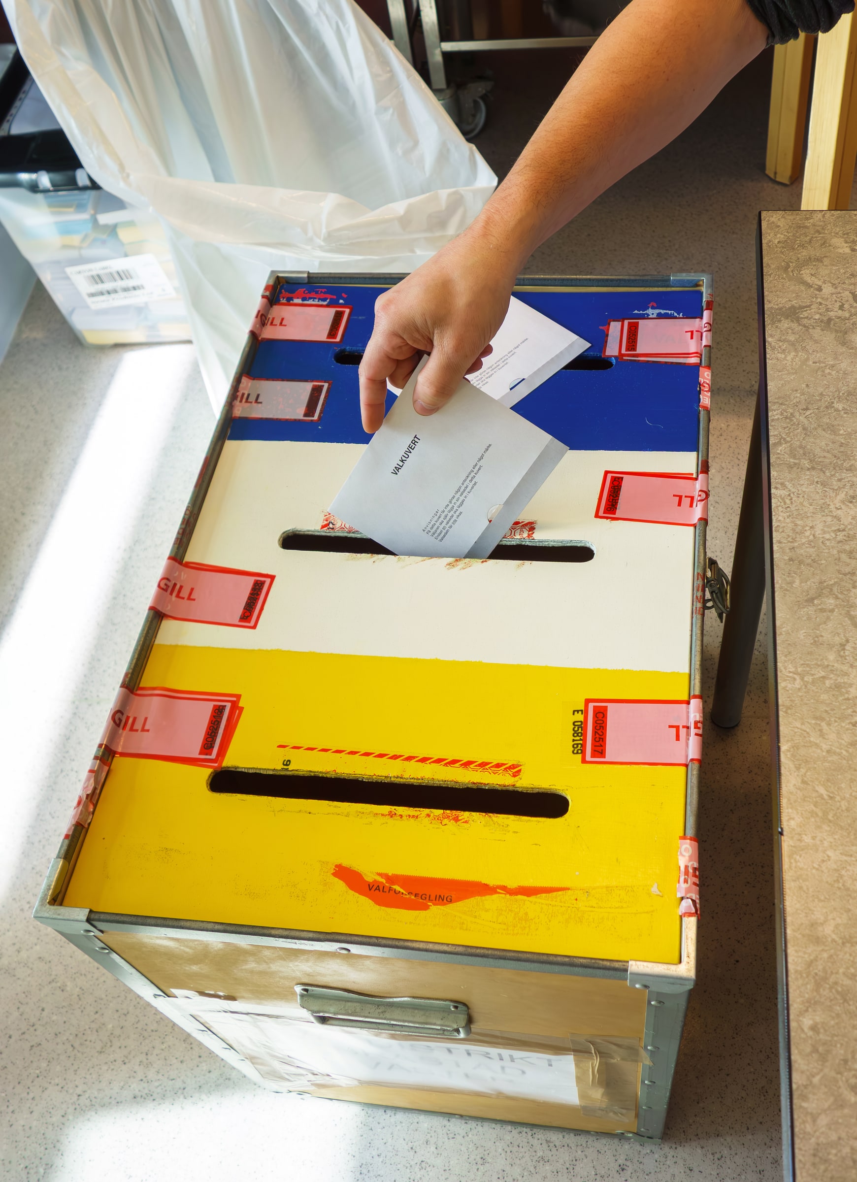 A voting official places a municipal ballot envelope into a sealed box in Brastad.