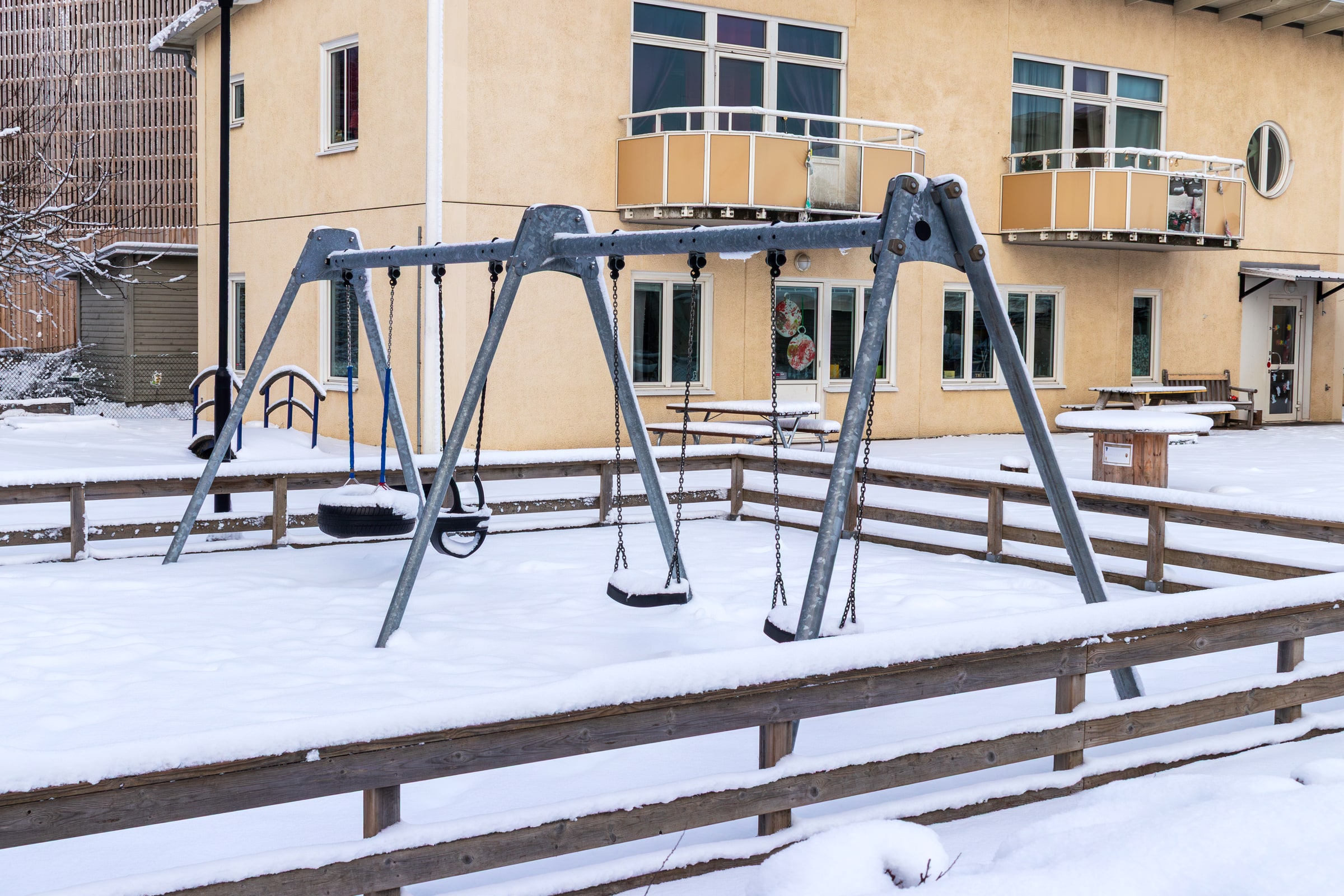 Swings stand in a snow-covered play yard at Asken preschool in Visby.