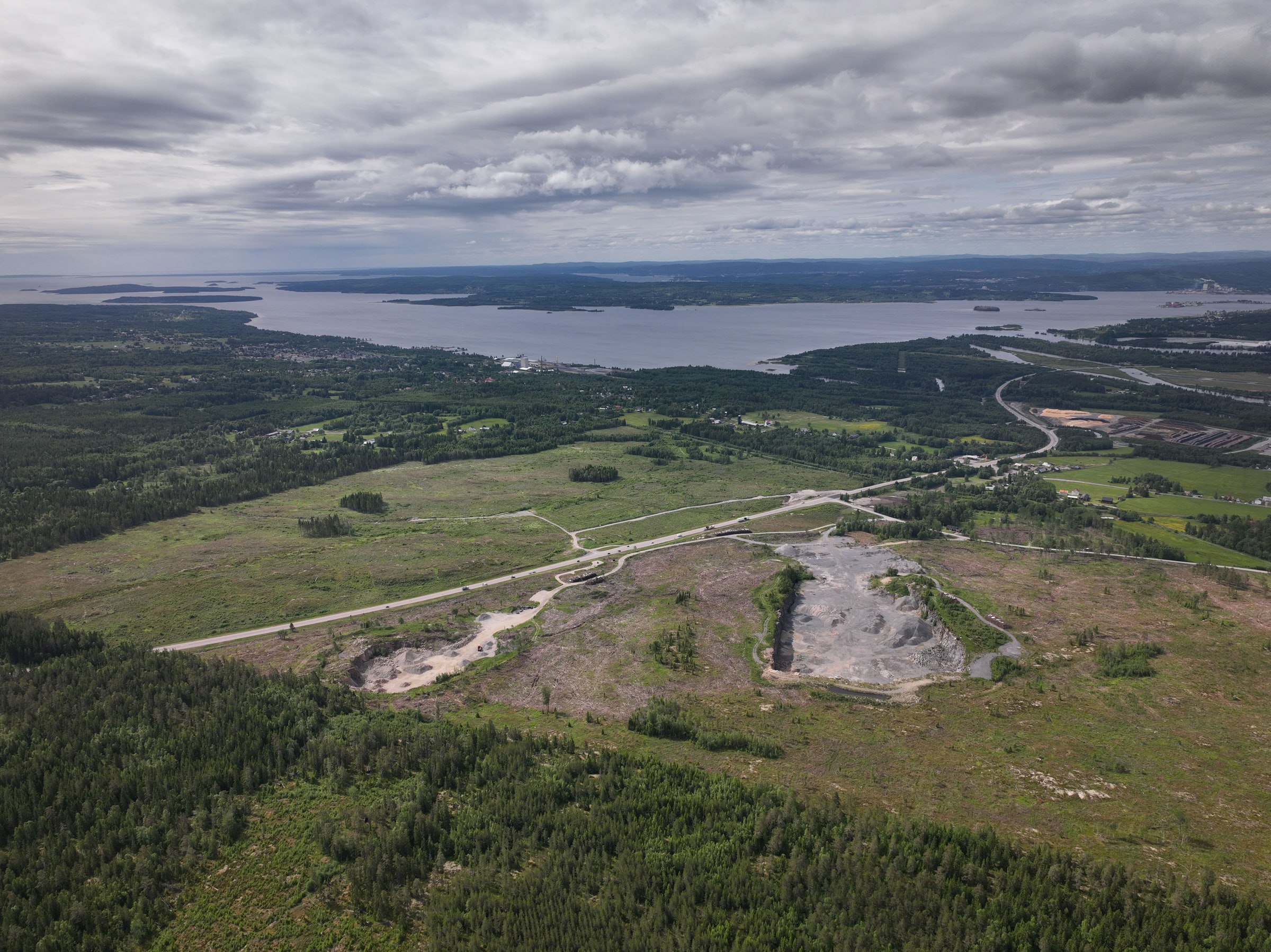 An aerial view of cleared land and access roads at Torsboda Industrial Park, surrounded by forest and water.