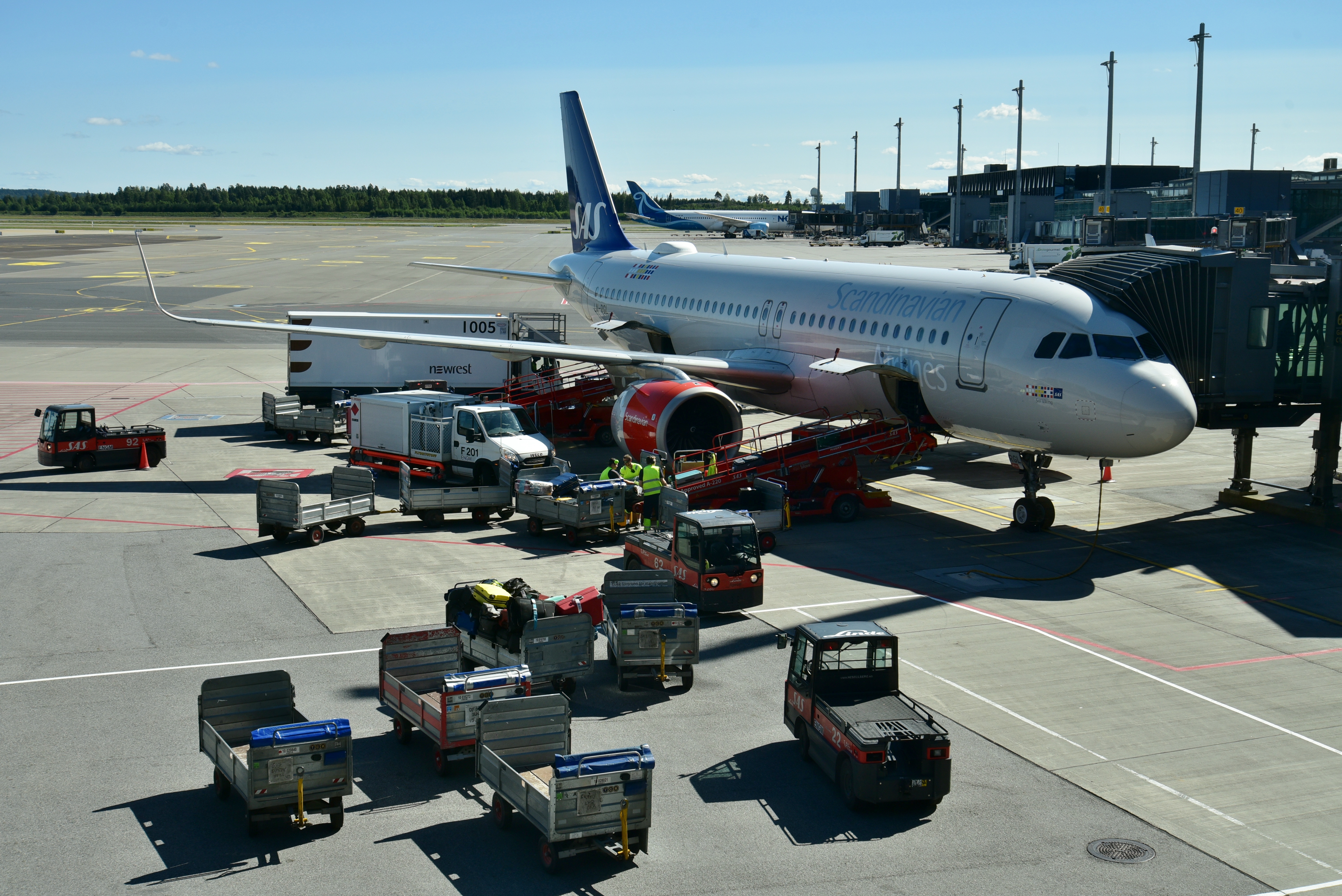 A Scandinavian Airlines Airbus A320 parked at Oslo Airport while ground crews service the aircraft.