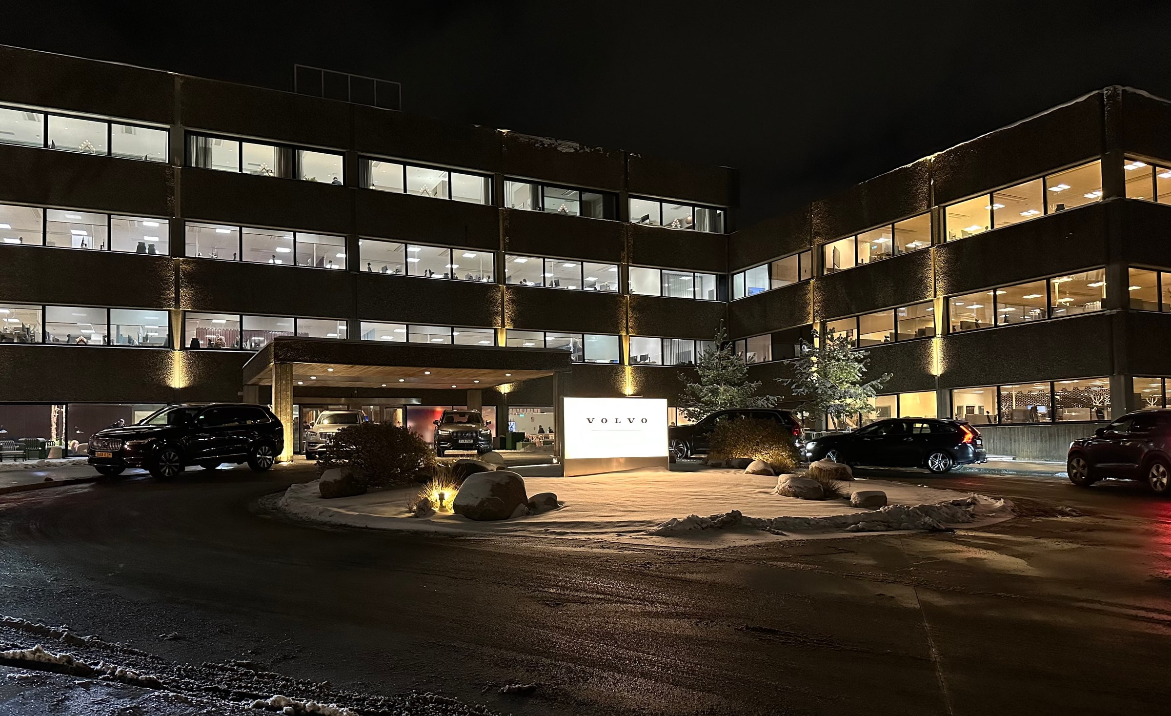 Illuminated offices and the entrance at Volvo Cars’ headquarters in Gothenburg, with snow on the ground.