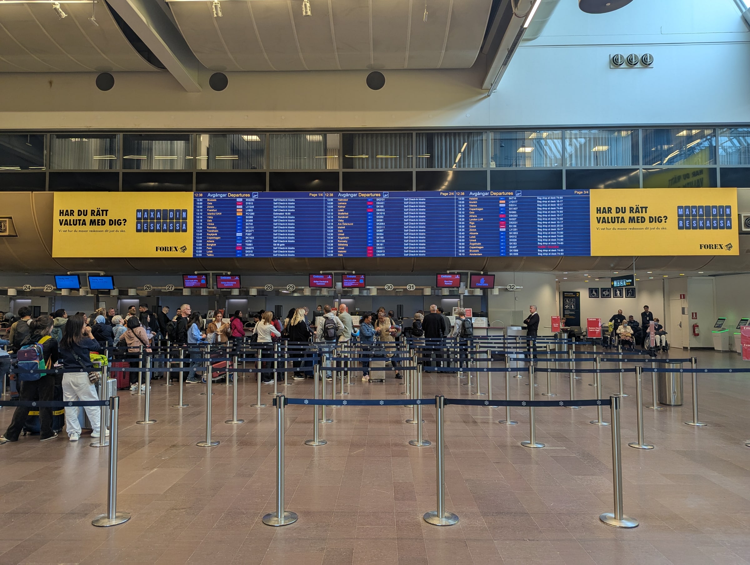 Passengers queue below departure-information screens at Stockholm Arlanda Terminal 5.