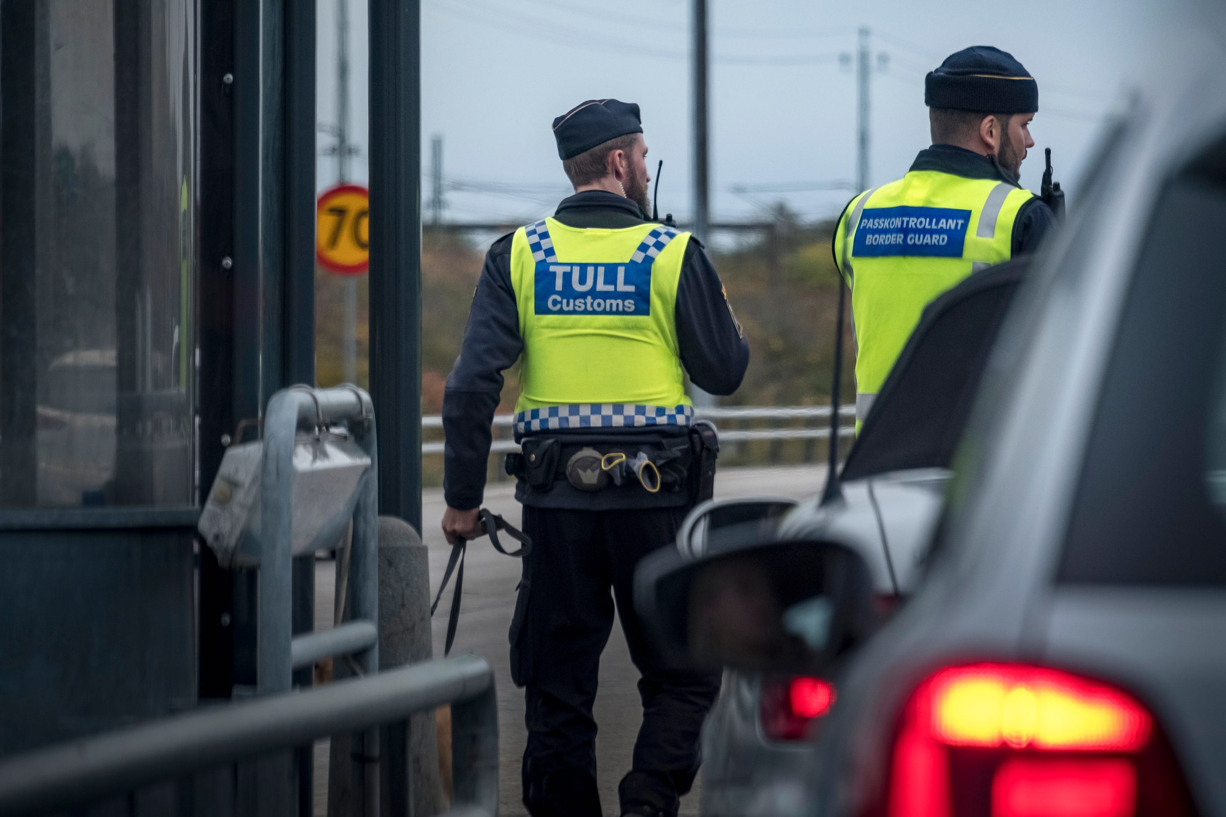 A customs officer and passport controller stand beside vehicles at the Lernacken checkpoint in Malmö.