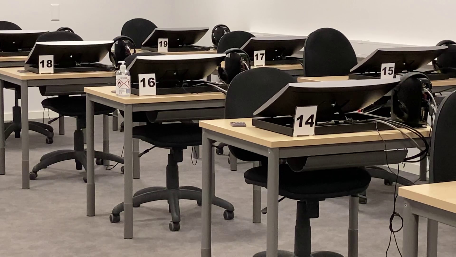 An empty Trafikverket Förarprov theory-test room with numbered computer stations and headphones.