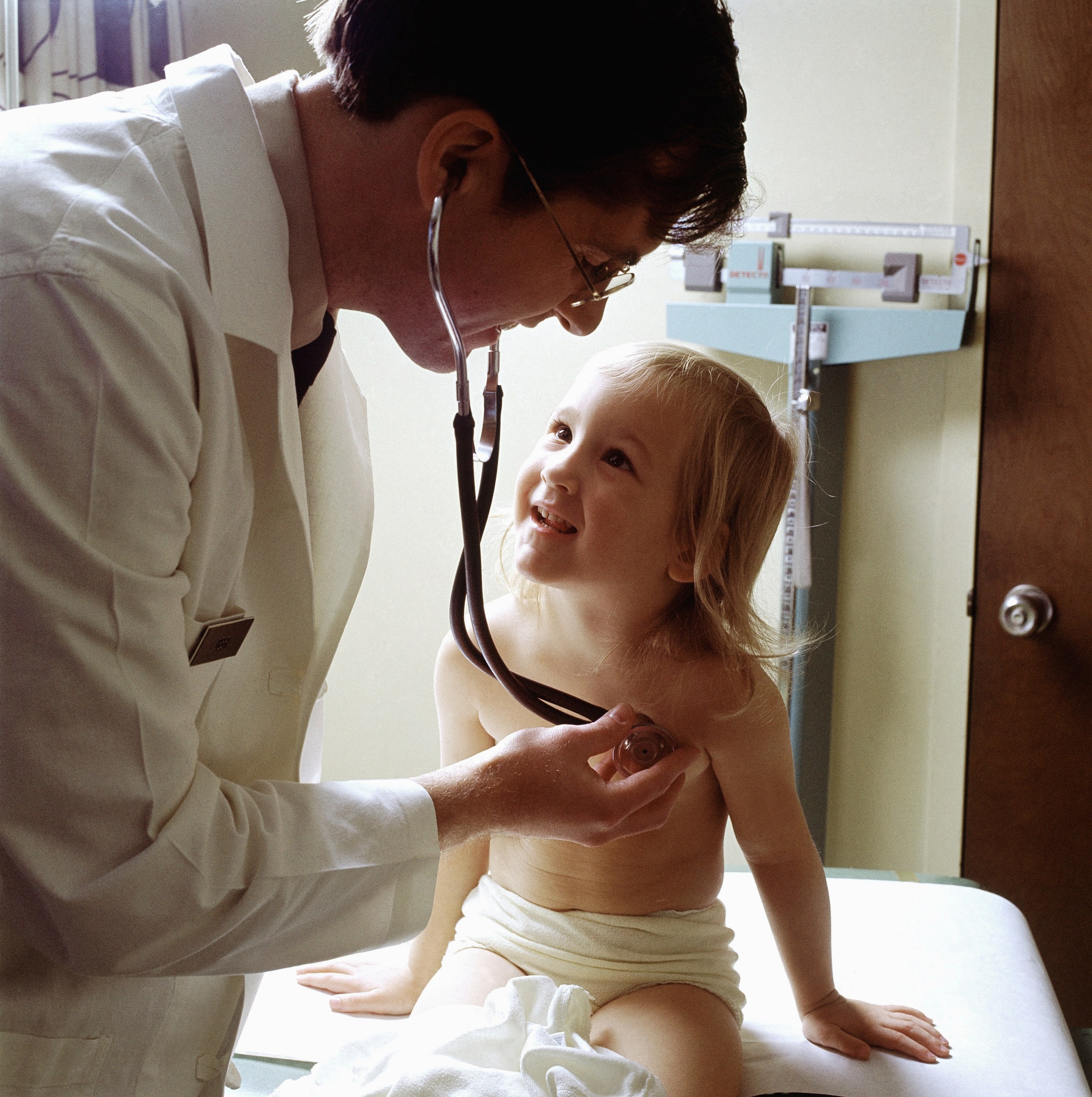A doctor uses a stethoscope to listen to a young patient's chest during a medical examination.