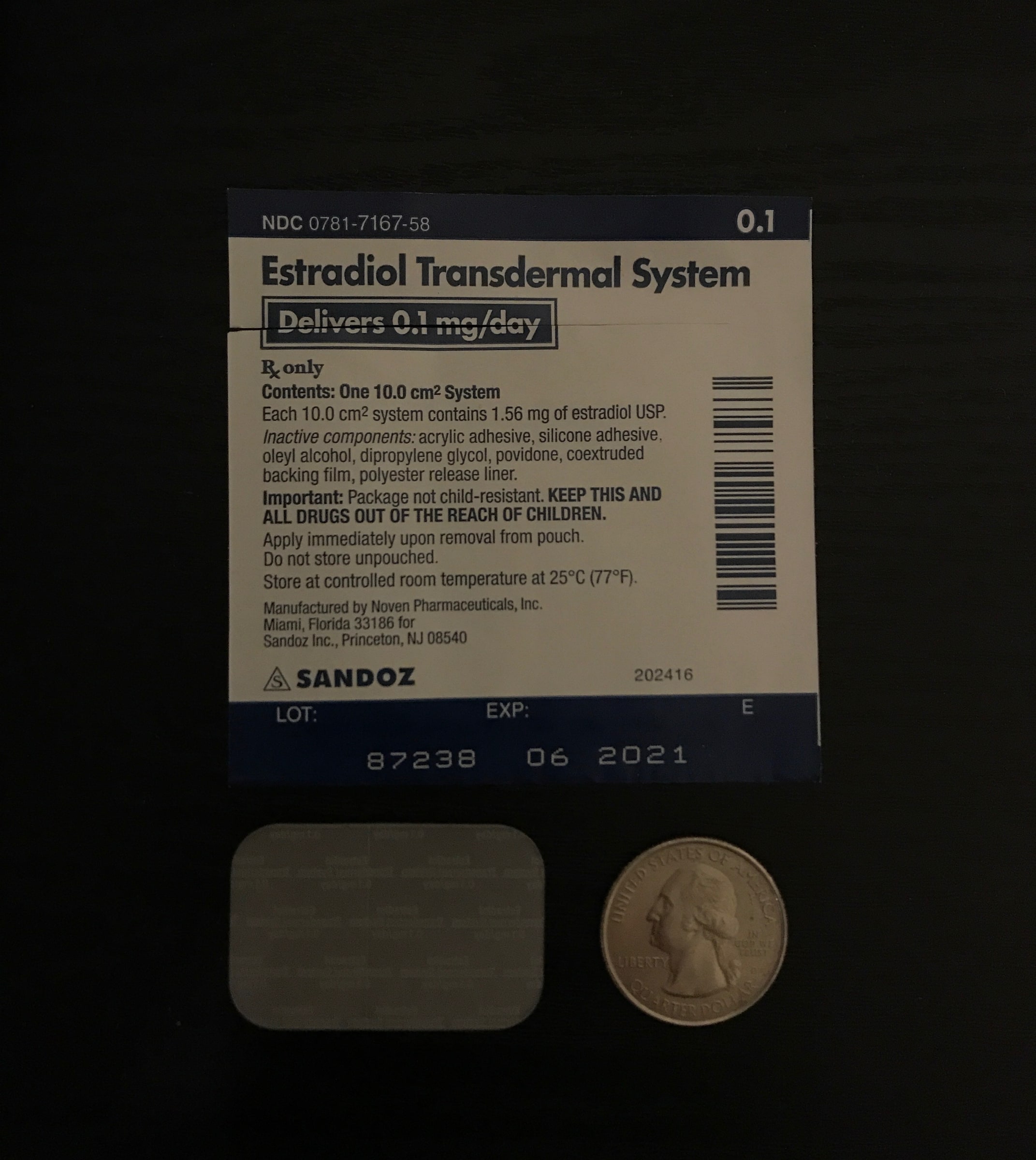 An estradiol transdermal medicine box beside a transparent skin patch and a coin for scale.