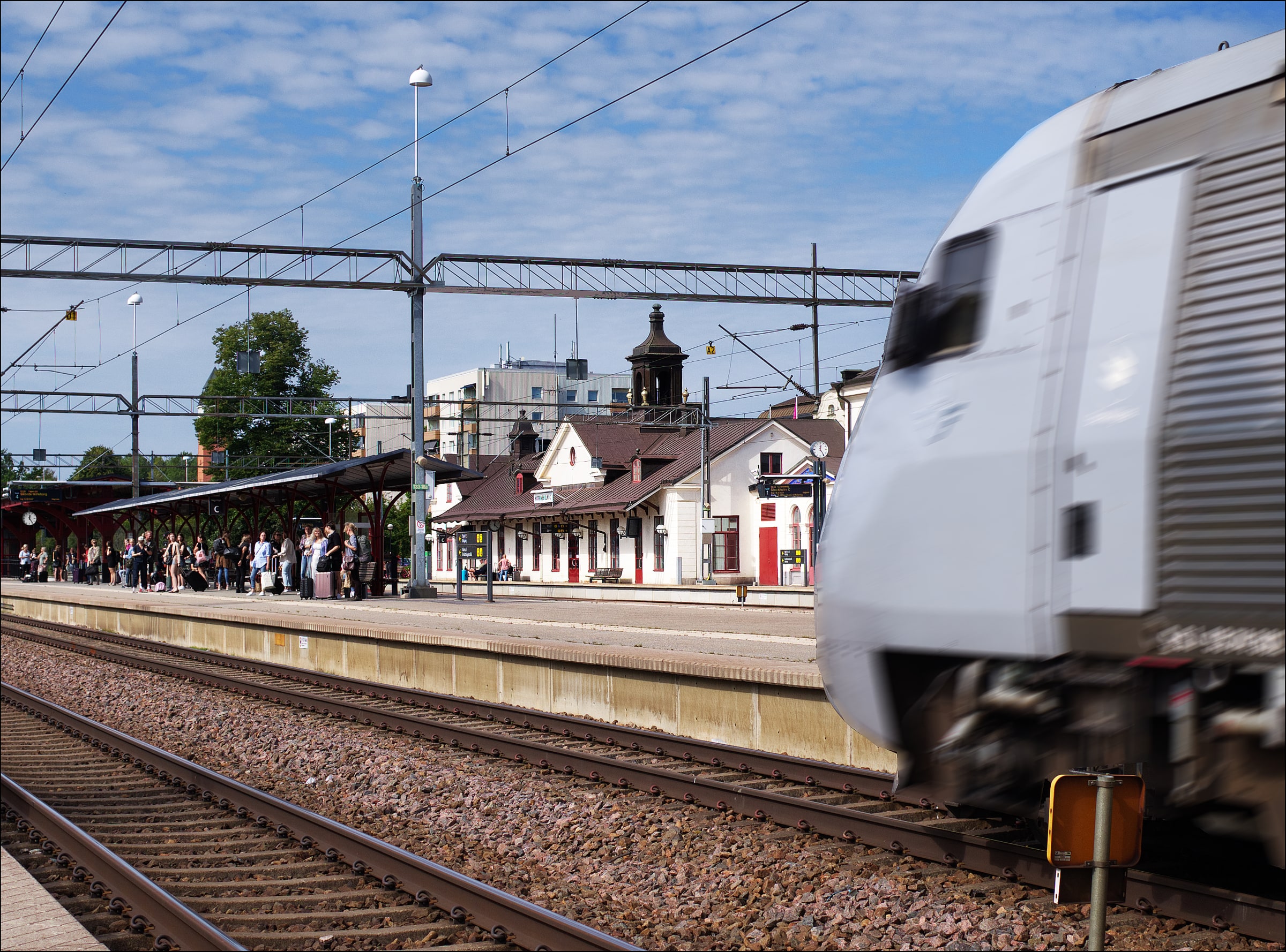 A train passes waiting travellers at Katrineholm Central station.