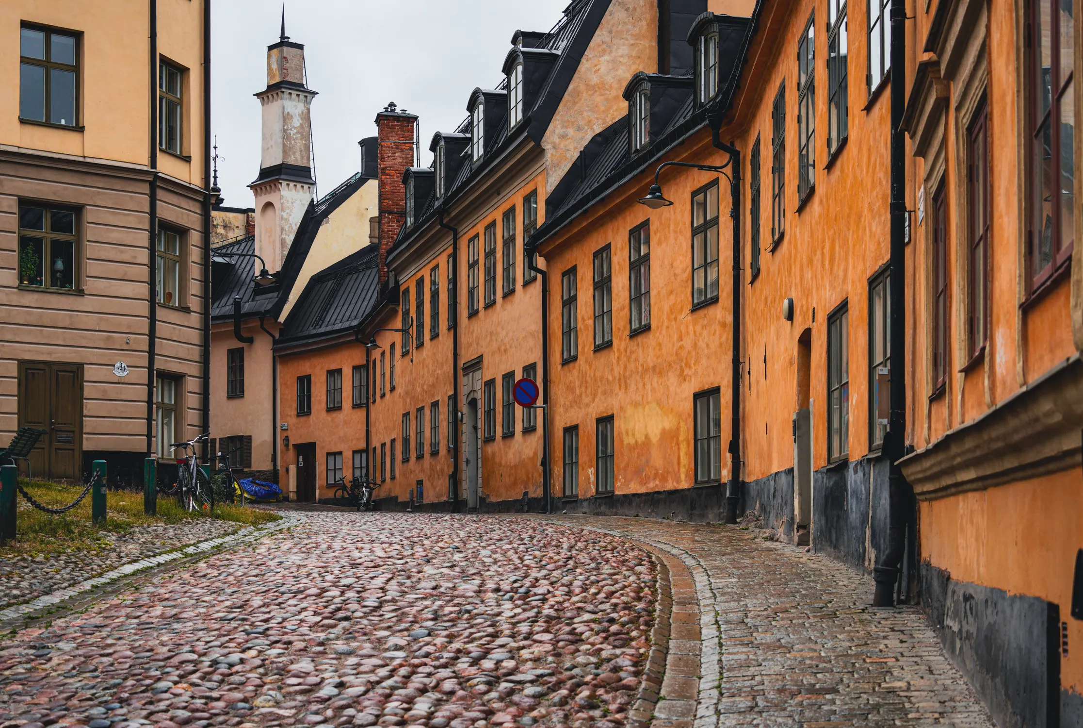 Historic orange and ochre buildings line a cobblestone street in Stockholm's Gamla Stan.