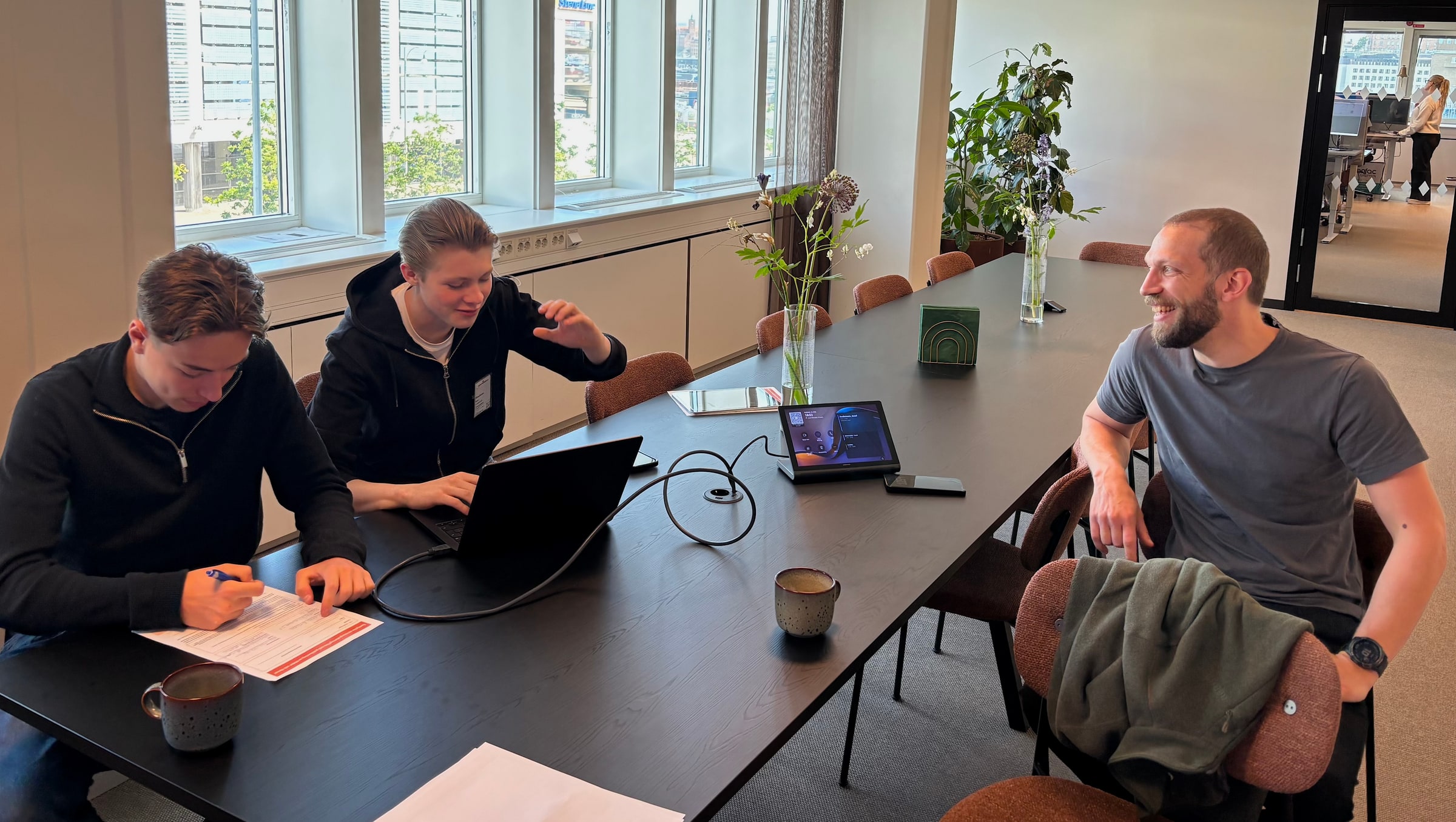 Two summer workers use laptops and review a document at Stena Fastigheter's Gothenburg office in June 2026.