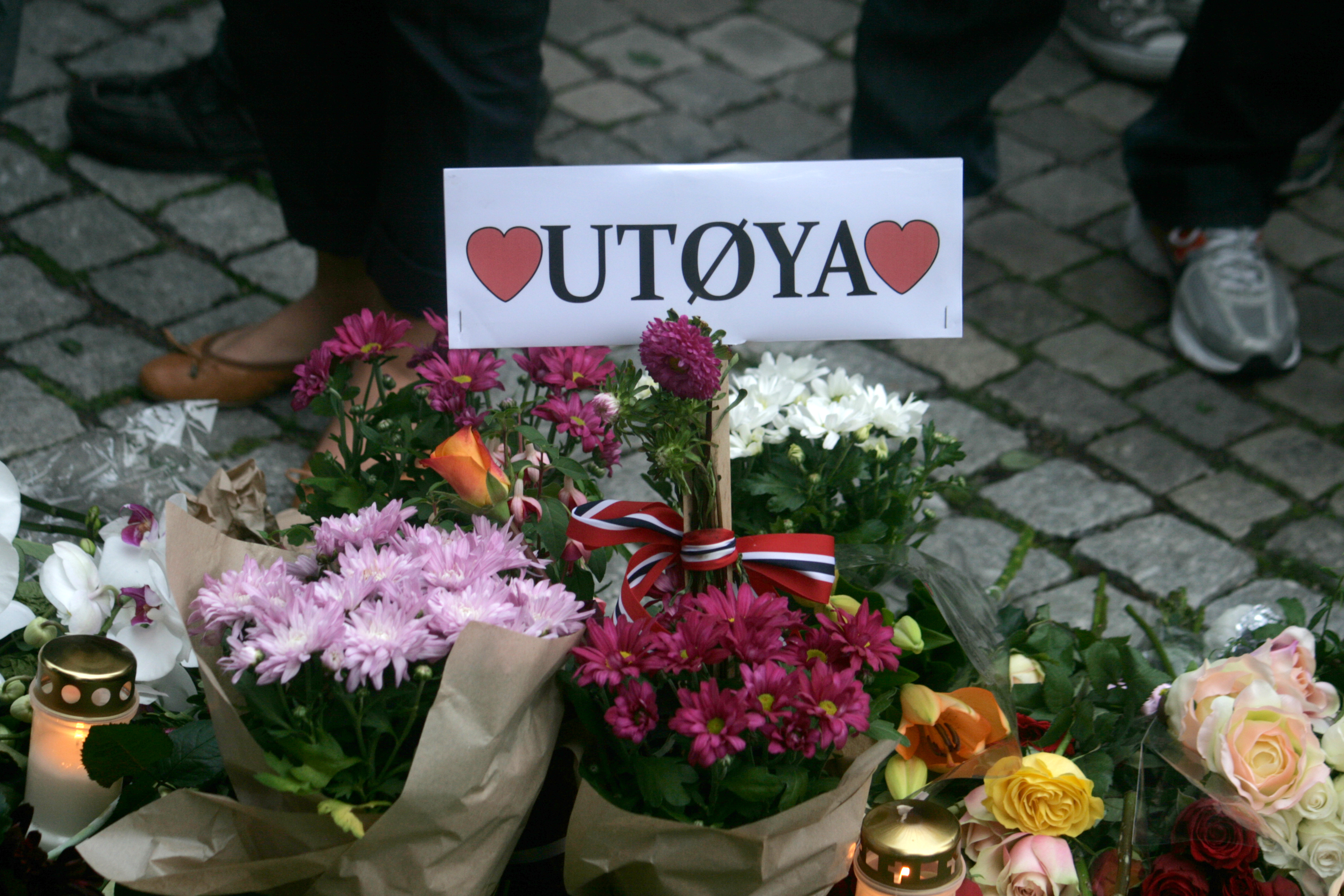 Flowers, candles, a Norwegian ribbon and a sign reading 'UTØYA' between red hearts at a memorial outside Oslo Cathedral.