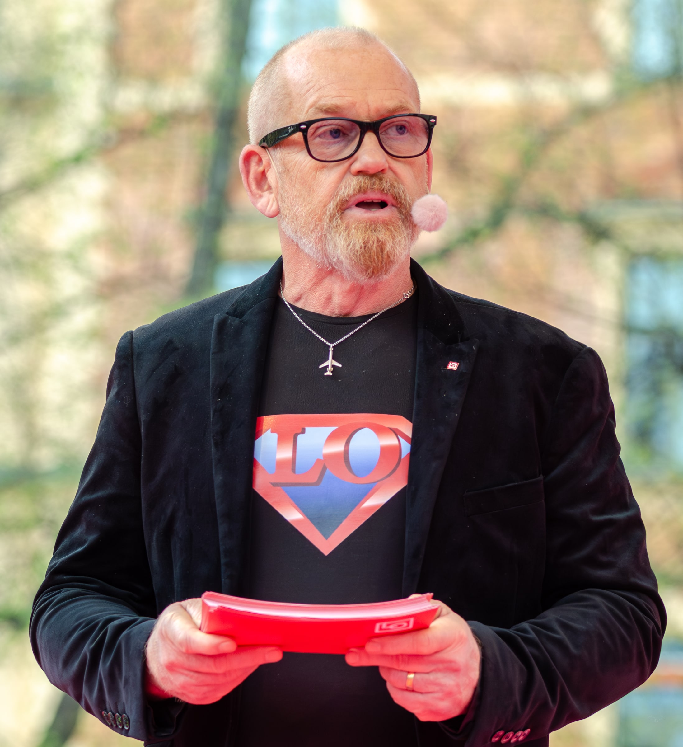 Johan Lindholm speaks through a headset microphone while holding red notes.