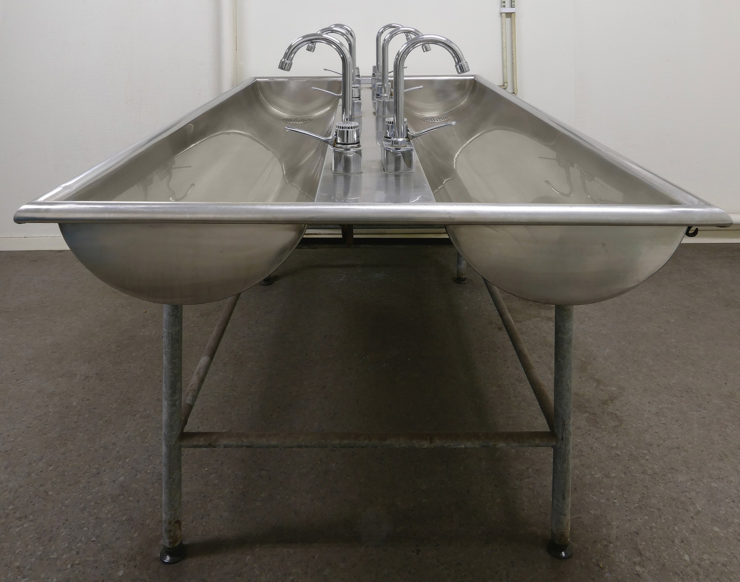 Chrome taps above stainless-steel washbasins in a workshop washroom in Gåseberg, Sweden, in January 2017.