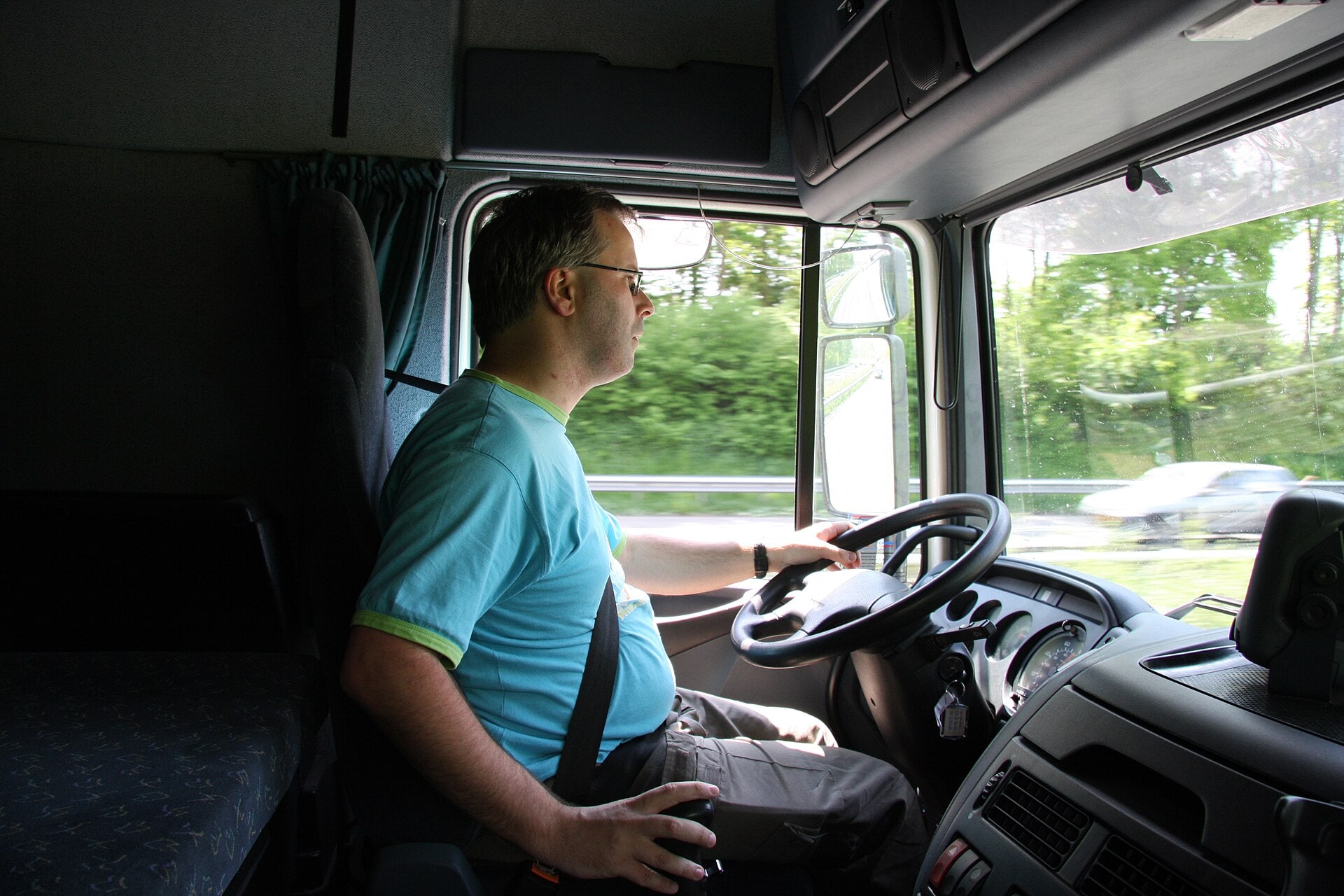 A professional truck driver seated inside the cab of a lorry.