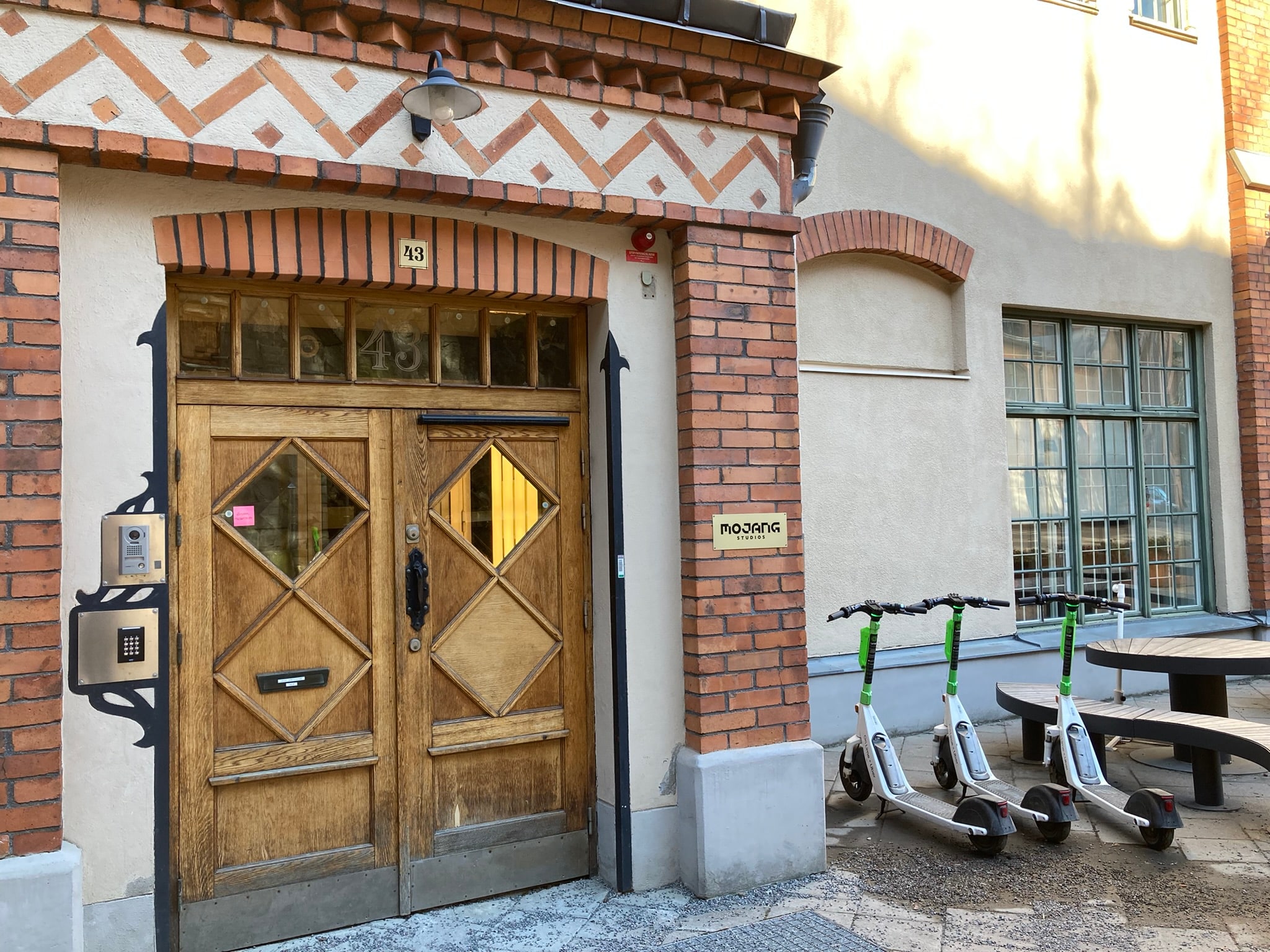 Wooden entrance doors and a Mojang Studios sign on a brick facade in Stockholm