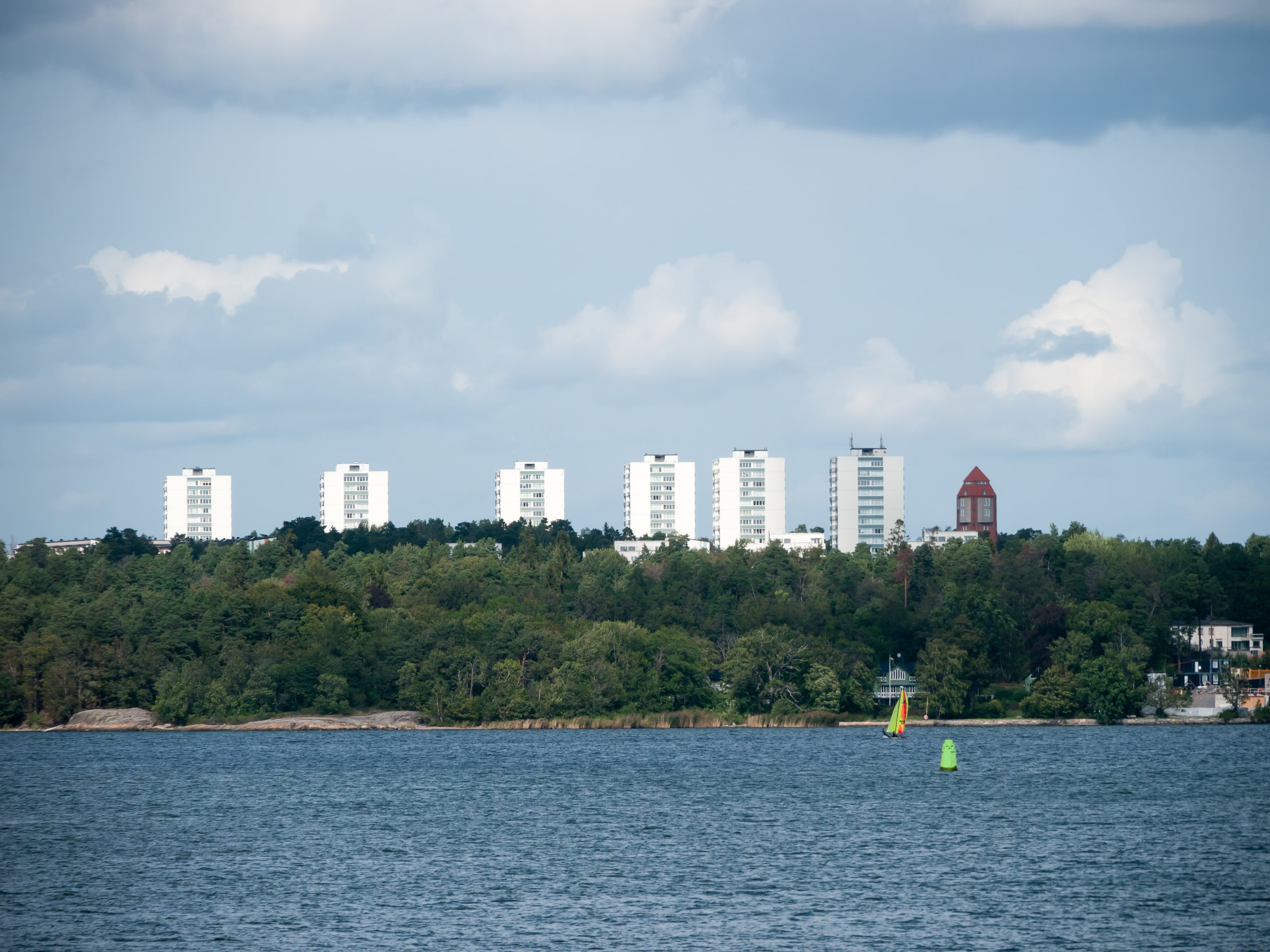 Apartment buildings rise above trees beside the water in Nacka, Greater Stockholm.