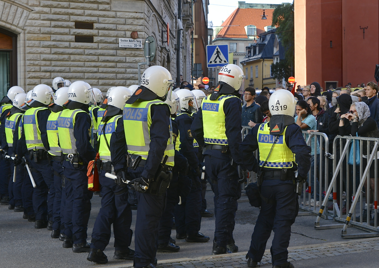 Swedish police officers stand between barriers and a crowd at a Stockholm rally in August 2014.