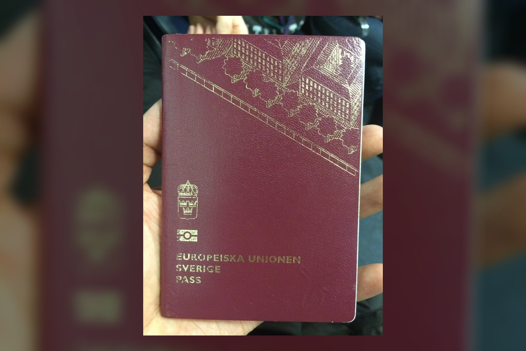 A Swedish passport held in one hand.