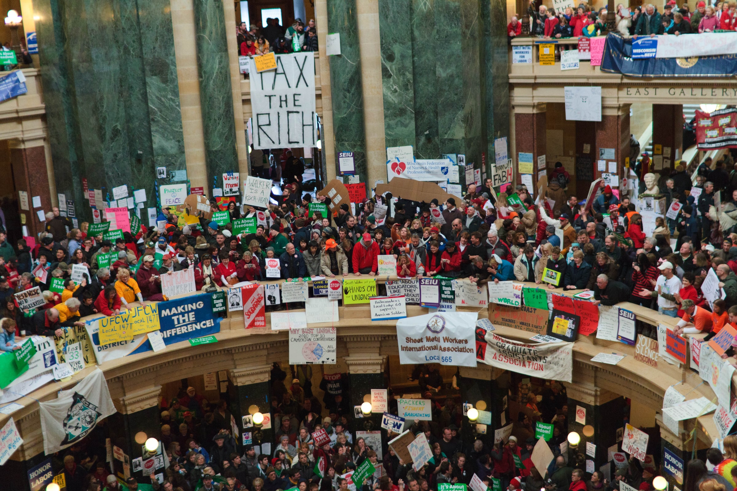 A large crowd gathers beneath a Tax the Rich banner inside the Wisconsin State Capitol in February 2011.