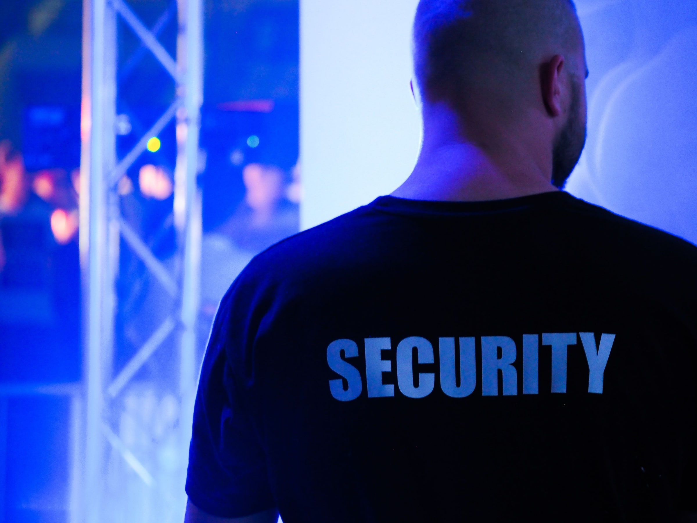 The back of a security worker in a black uniform at an entrance.