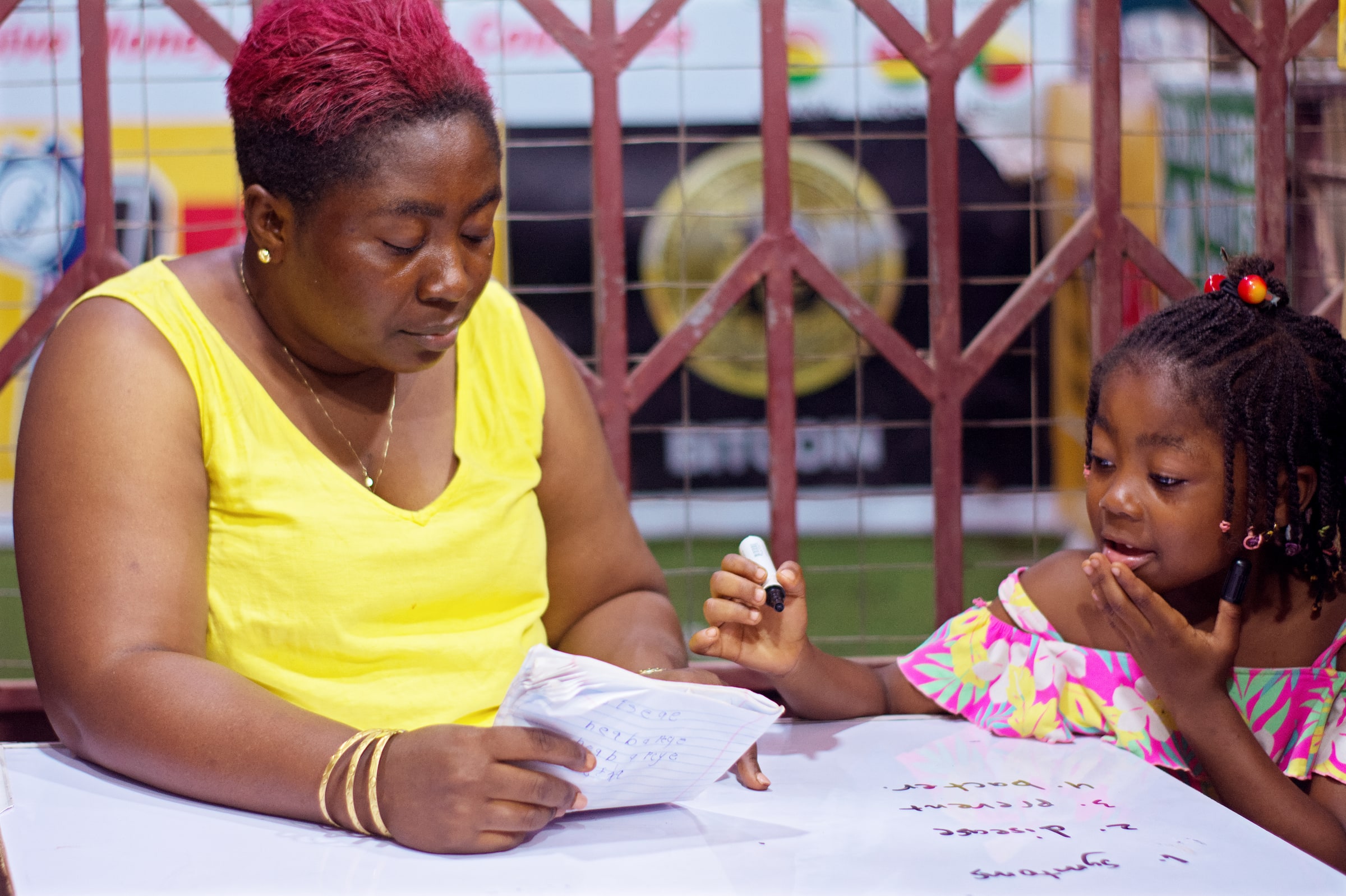 A mother helps her child with handwritten homework at a table.