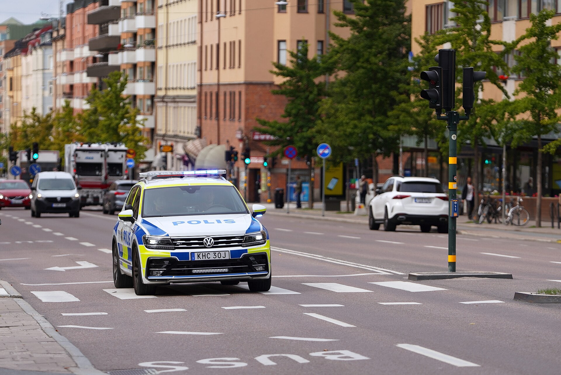 A Swedish police car drives through Stockholm with its emergency lights activated.