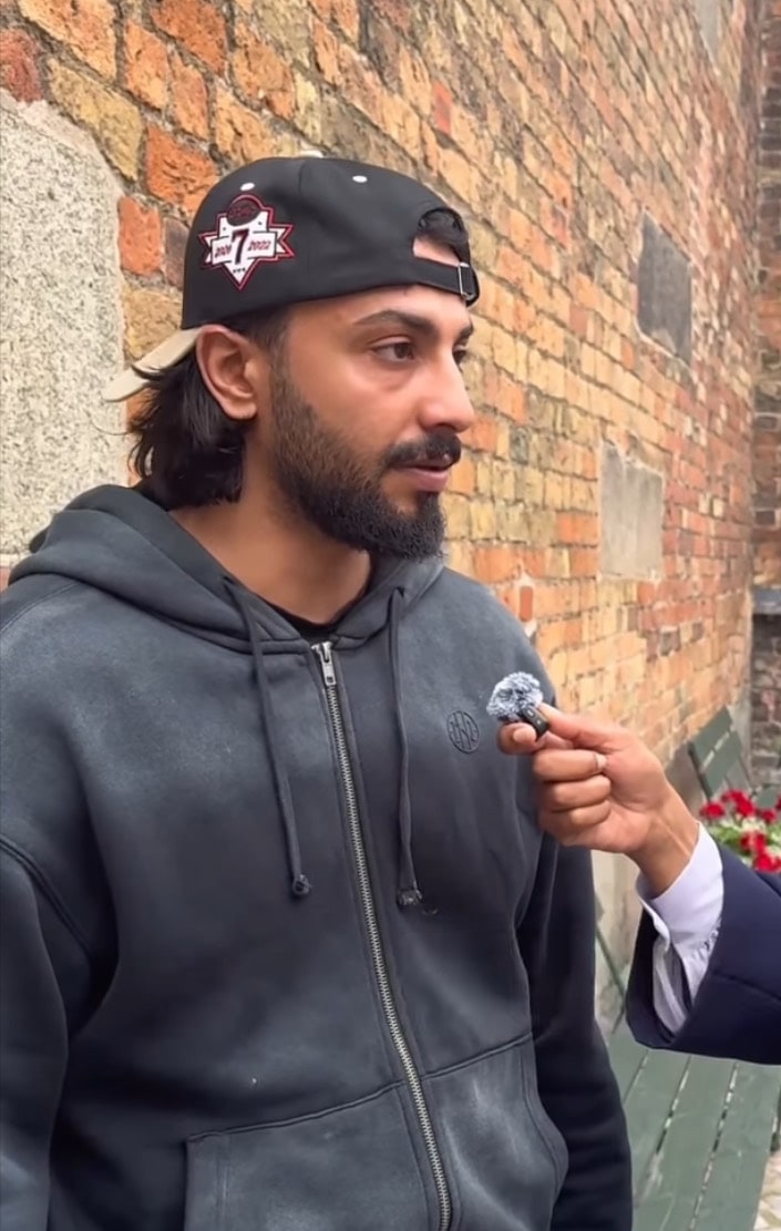 Mohammed Nour Oklah speaks to an interviewer beside a brick wall.