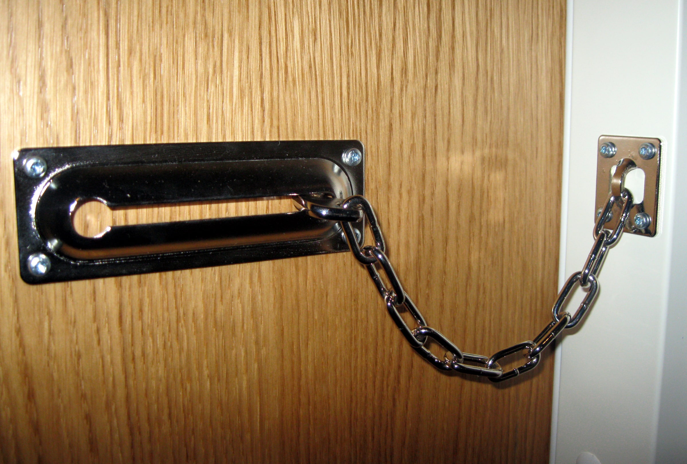 A metal security chain fastened across a closed wooden door.