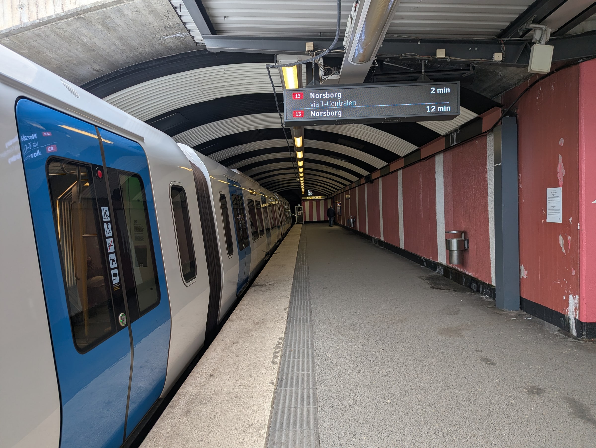 A blue-and-white metro train stands beside the platform at Ropsten station in Stockholm.